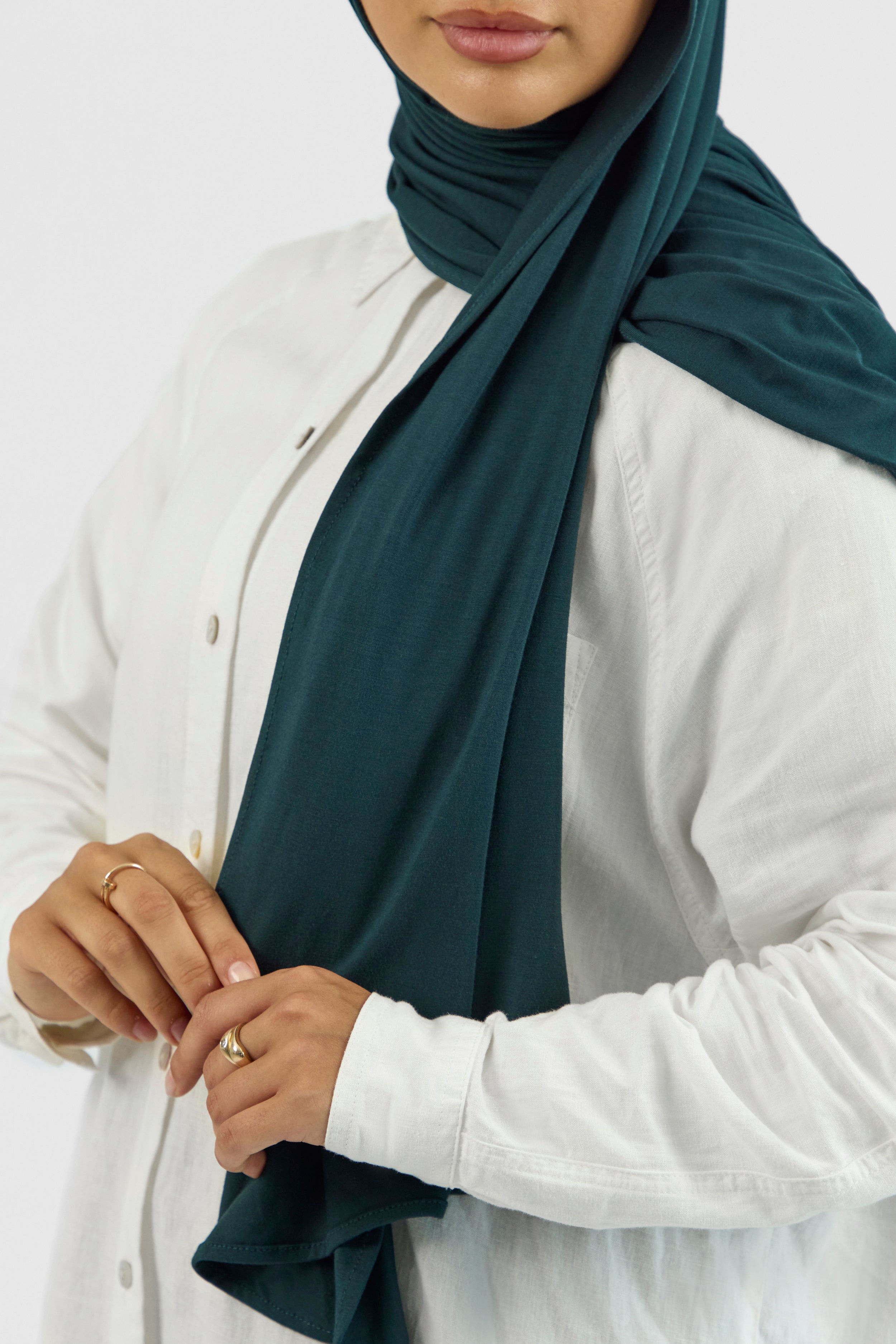 A close-up of a woman wearing a matching jersey hijab set. Colour description: dark teal.