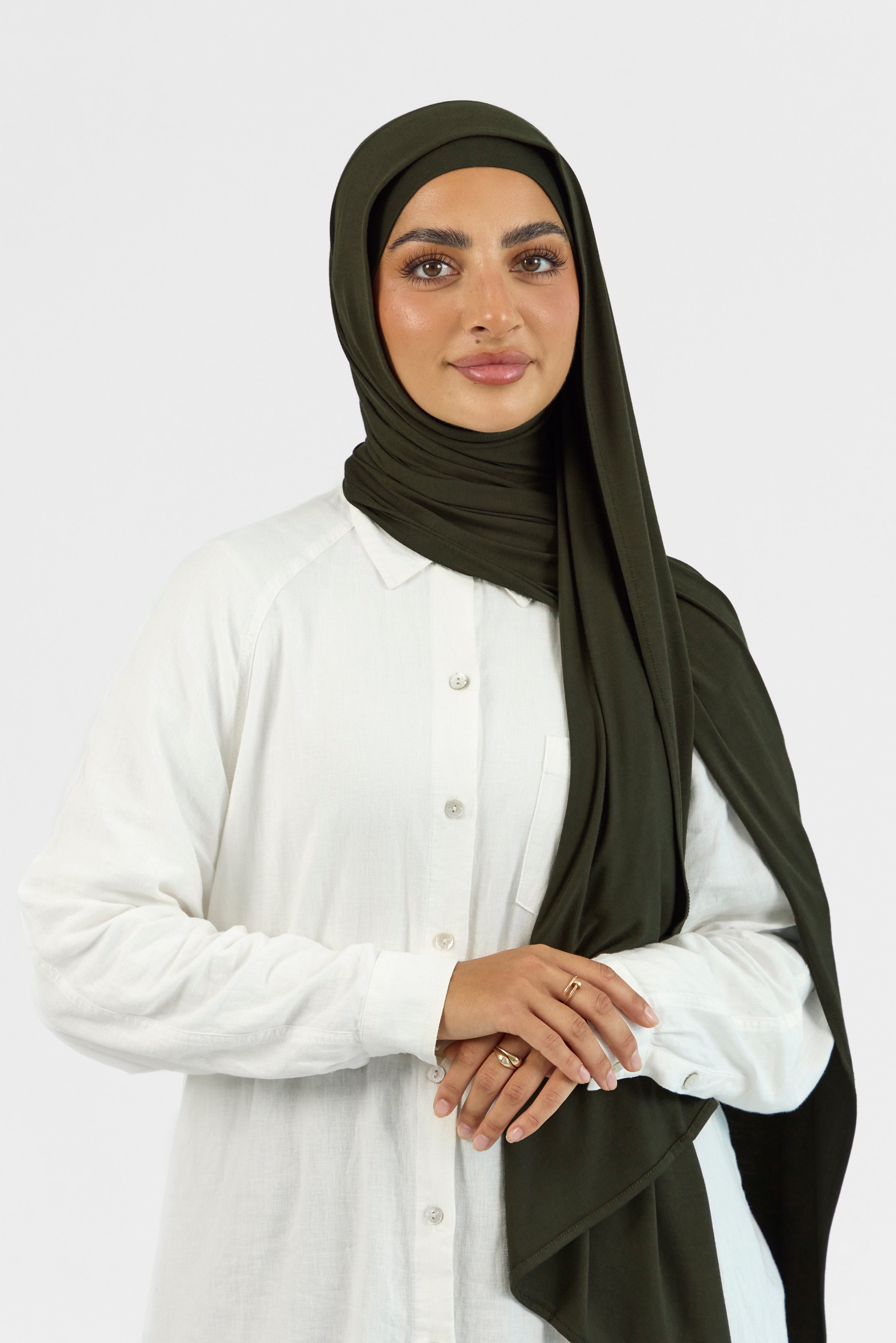 A female model wearing a matching jersey hijab set. The model is crossing her arms. Colour description: dark green.