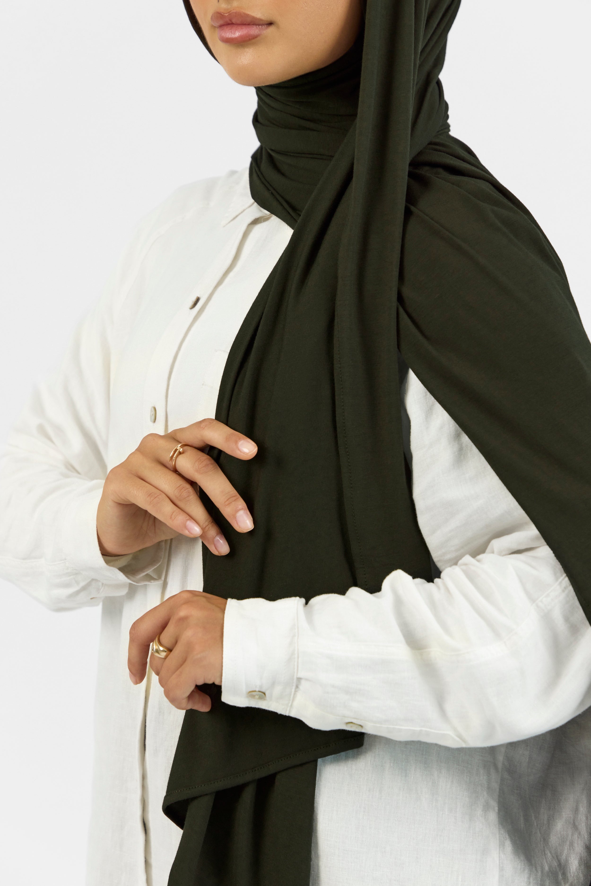 A close-up of a woman wearing a matching jersey hijab set. The model is turned to the left. Colour description: dark green.