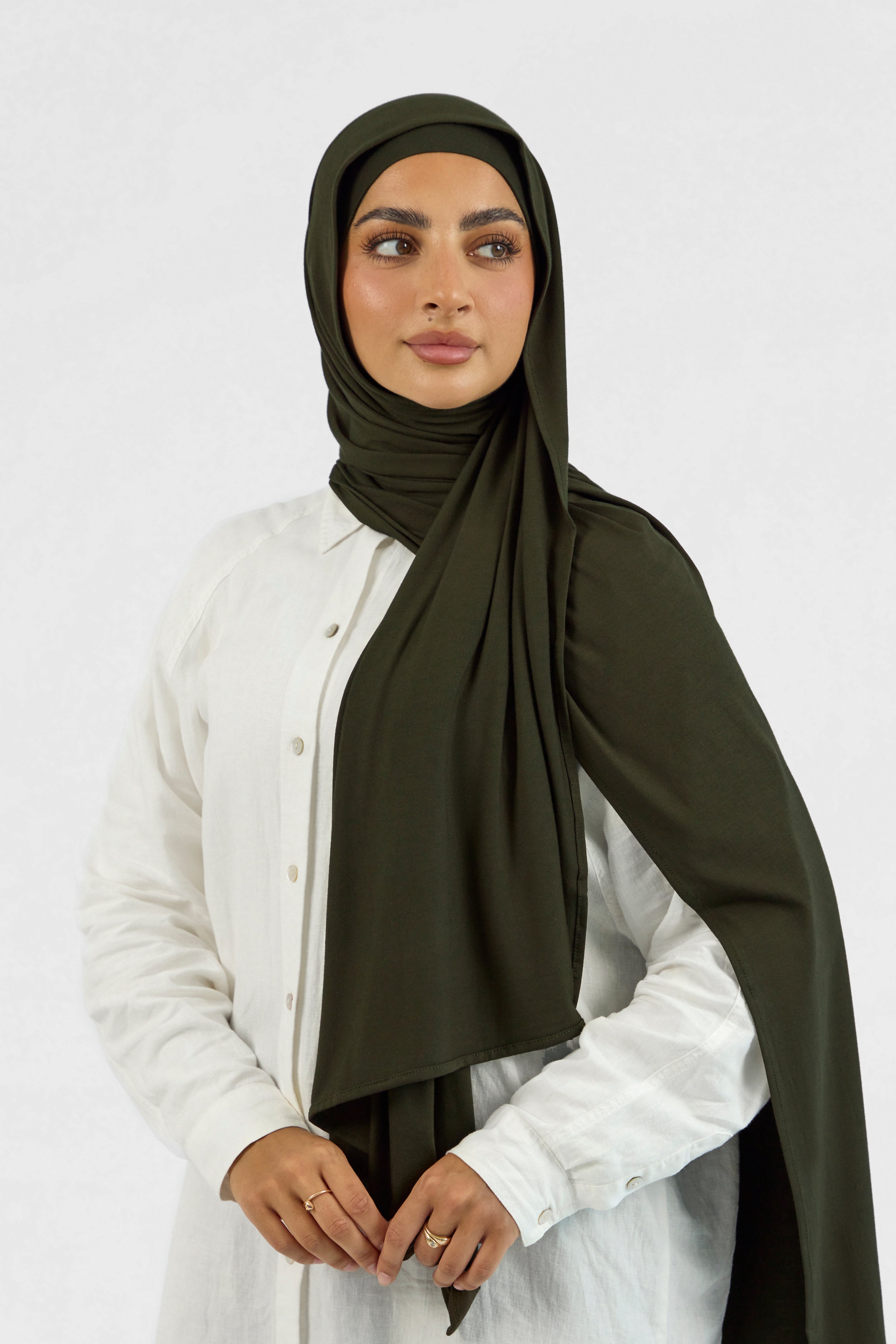A female model wearing a matching jersey hijab set. The model is looking to the right. Colour description: dark green.