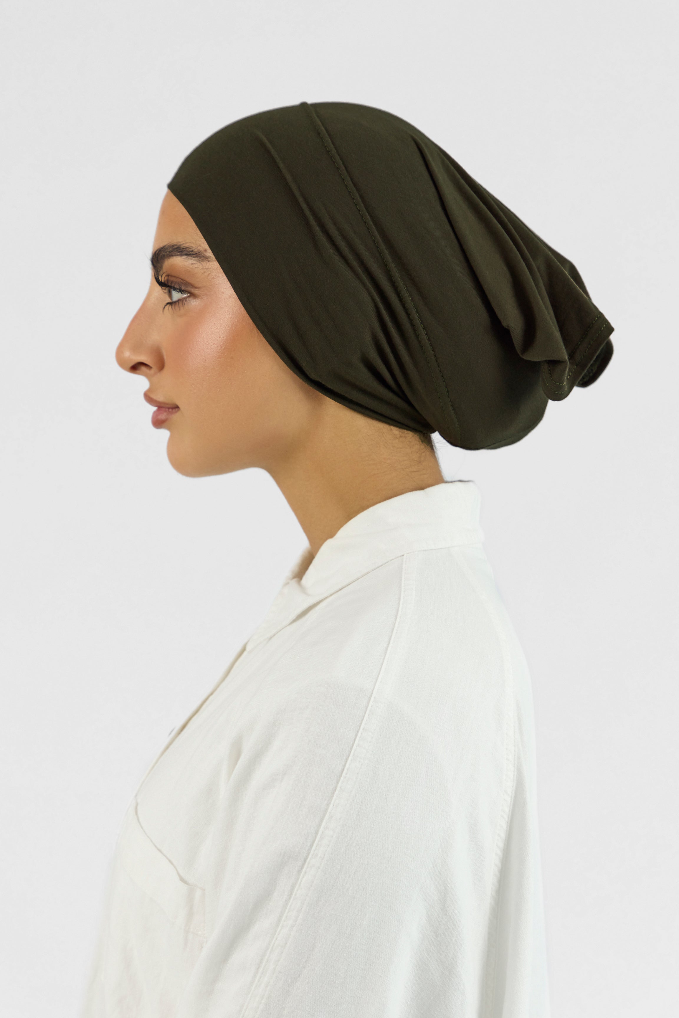 The left profile of a female model wearing a hijab undercap. Colour description: dark green.