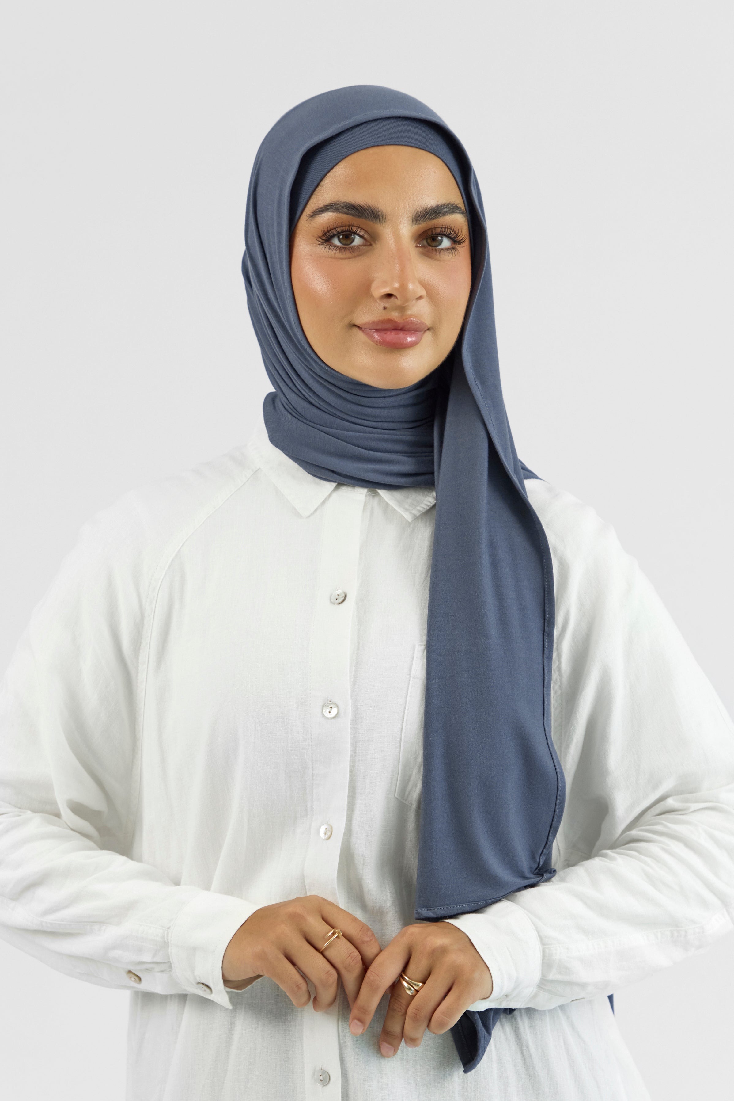 The front of a female model wearing a matching jersey hijab set. This set includes a modal jersey hijab and matching undercap. Colour description: denim blue.