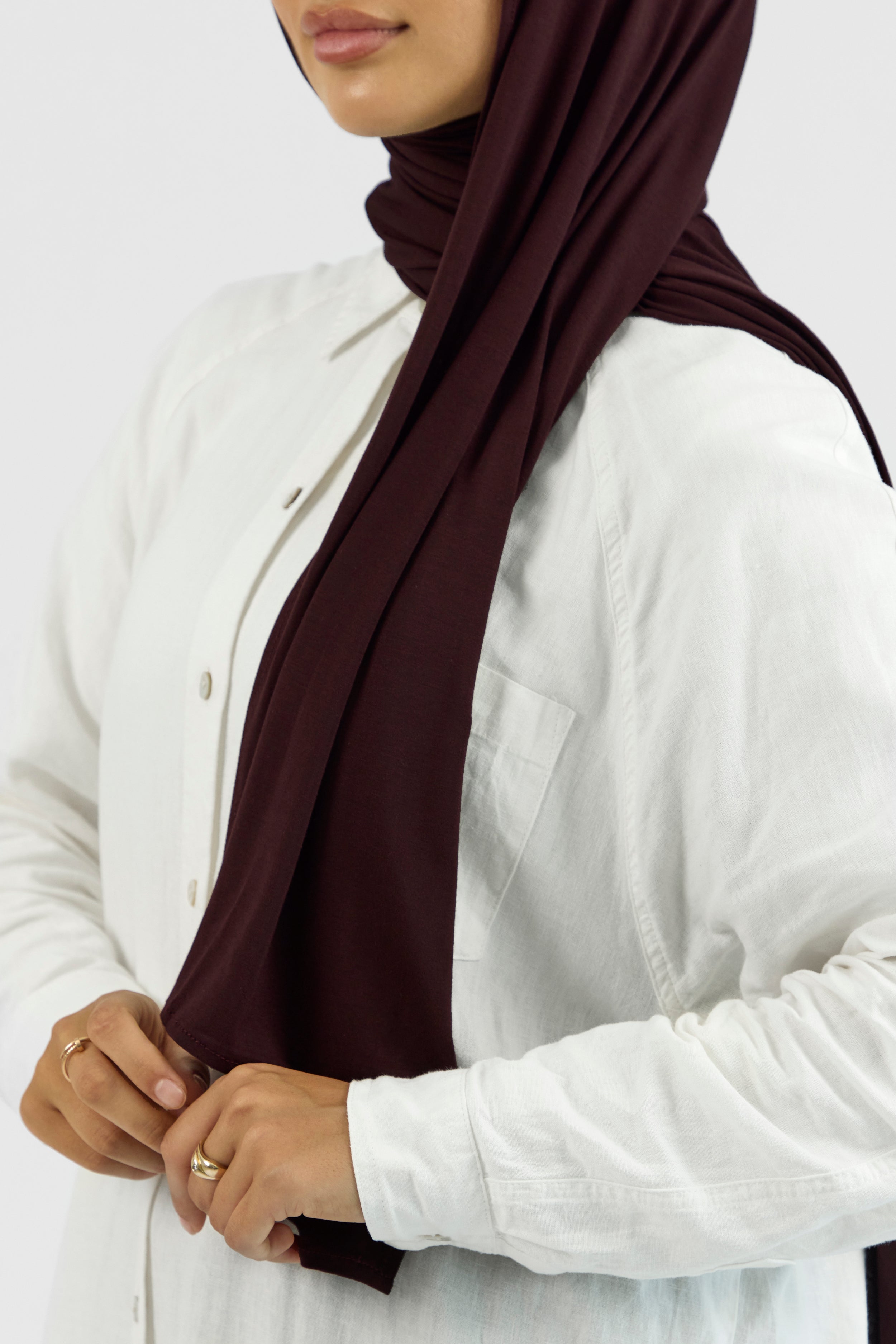 A close-up of a woman wearing a matching jersey hijab set. The model is turned to the left. Colour description: deep plum.