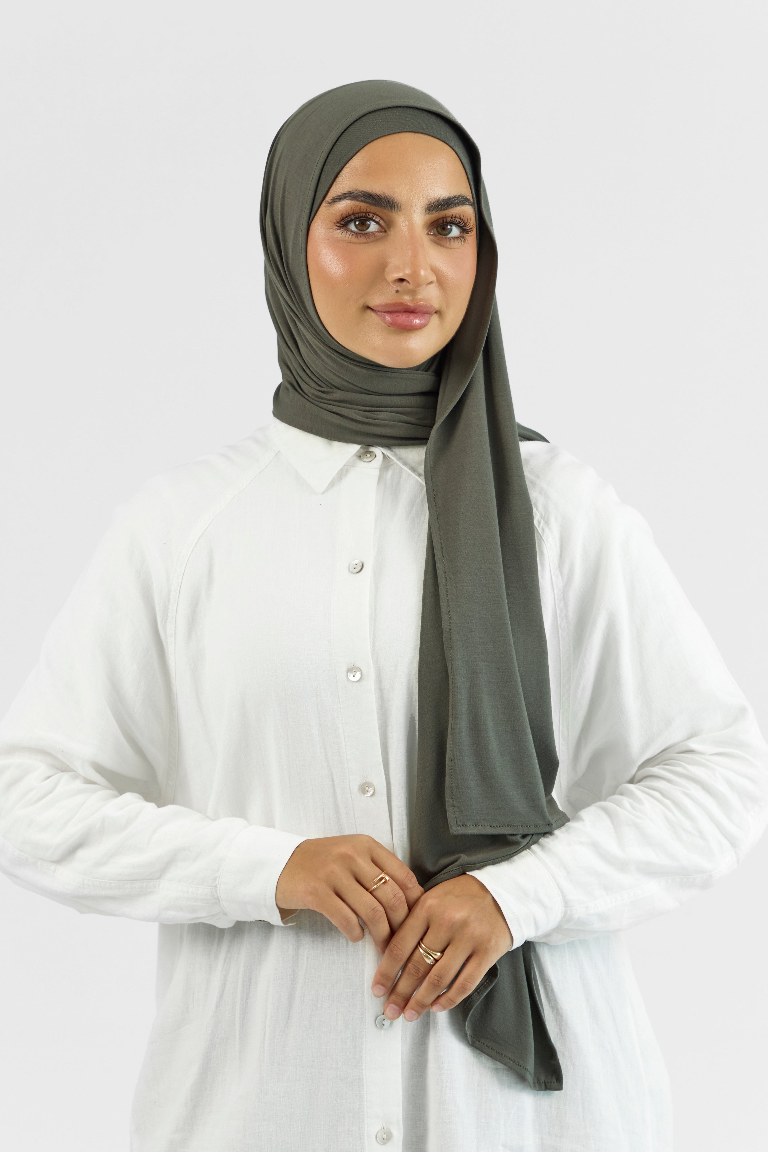 A woman wearing a matching jersey hijab set. This set includes a modal jersey hijab and matching undercap. Colour description: muted green.