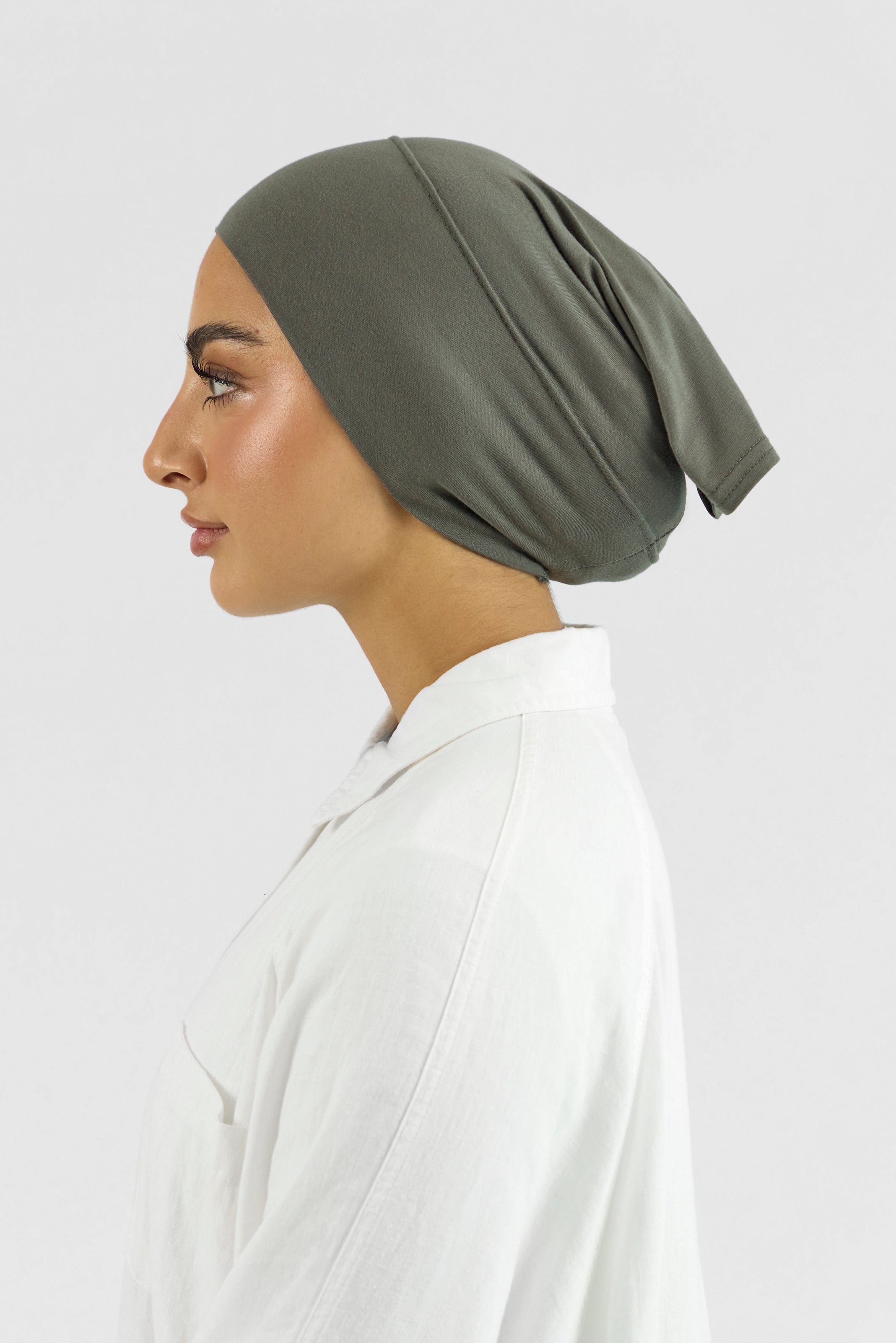 The left profile of a female model wearing a hijab undercap. Colour description: muted green.