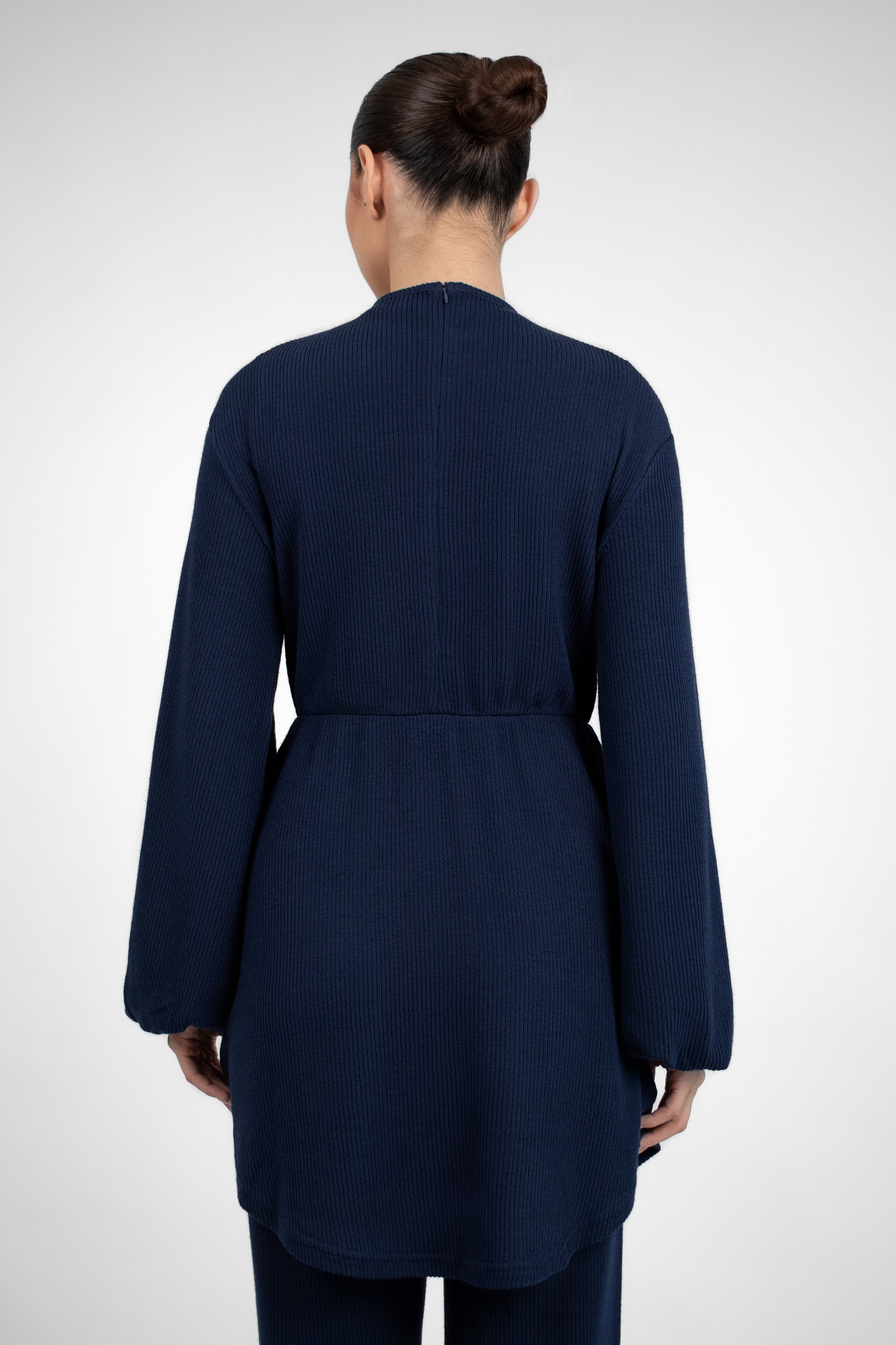 A back pose from a model in a Knit Peplum Top.	Colour: Navy