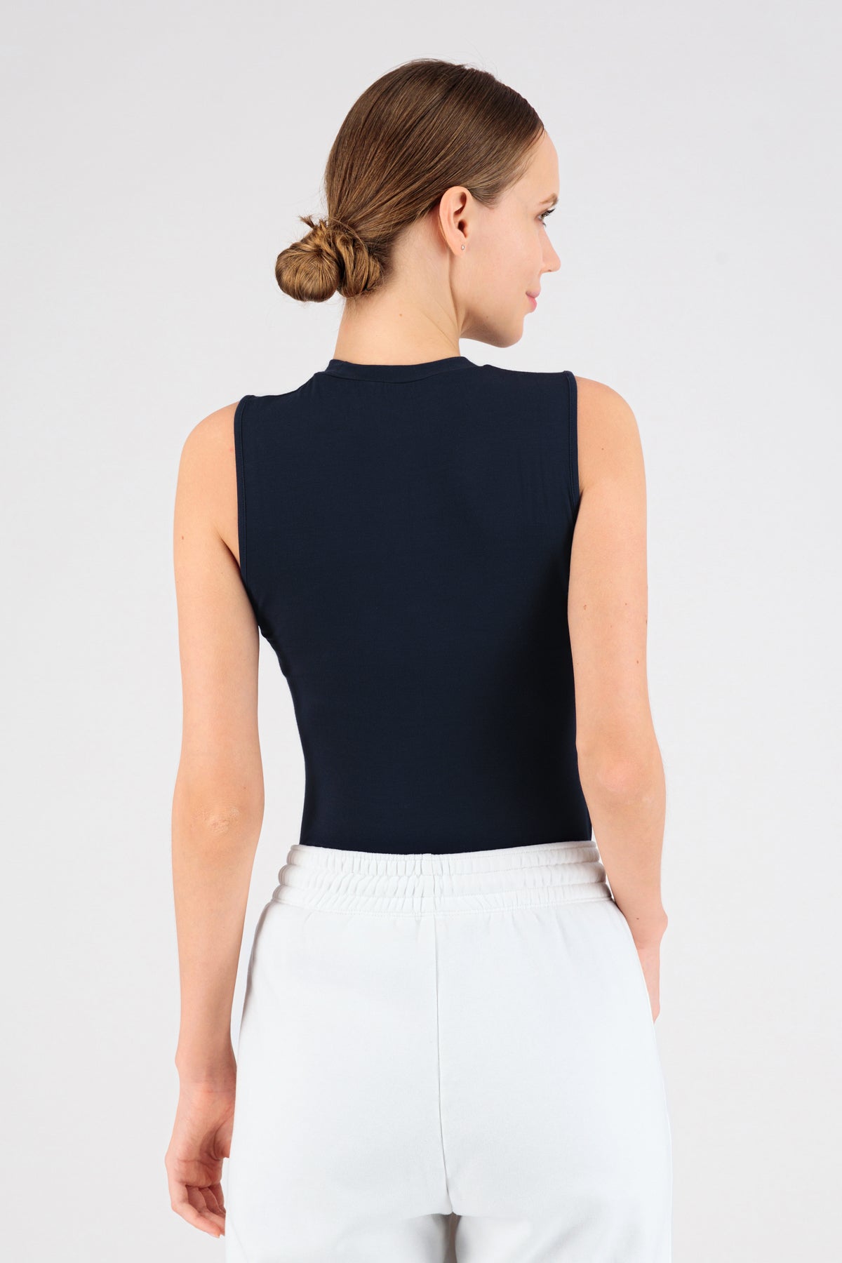 A girl wearing FARES' sleeveless layer is shown from the back. Her head is turned to the right. Colour description: Navy.