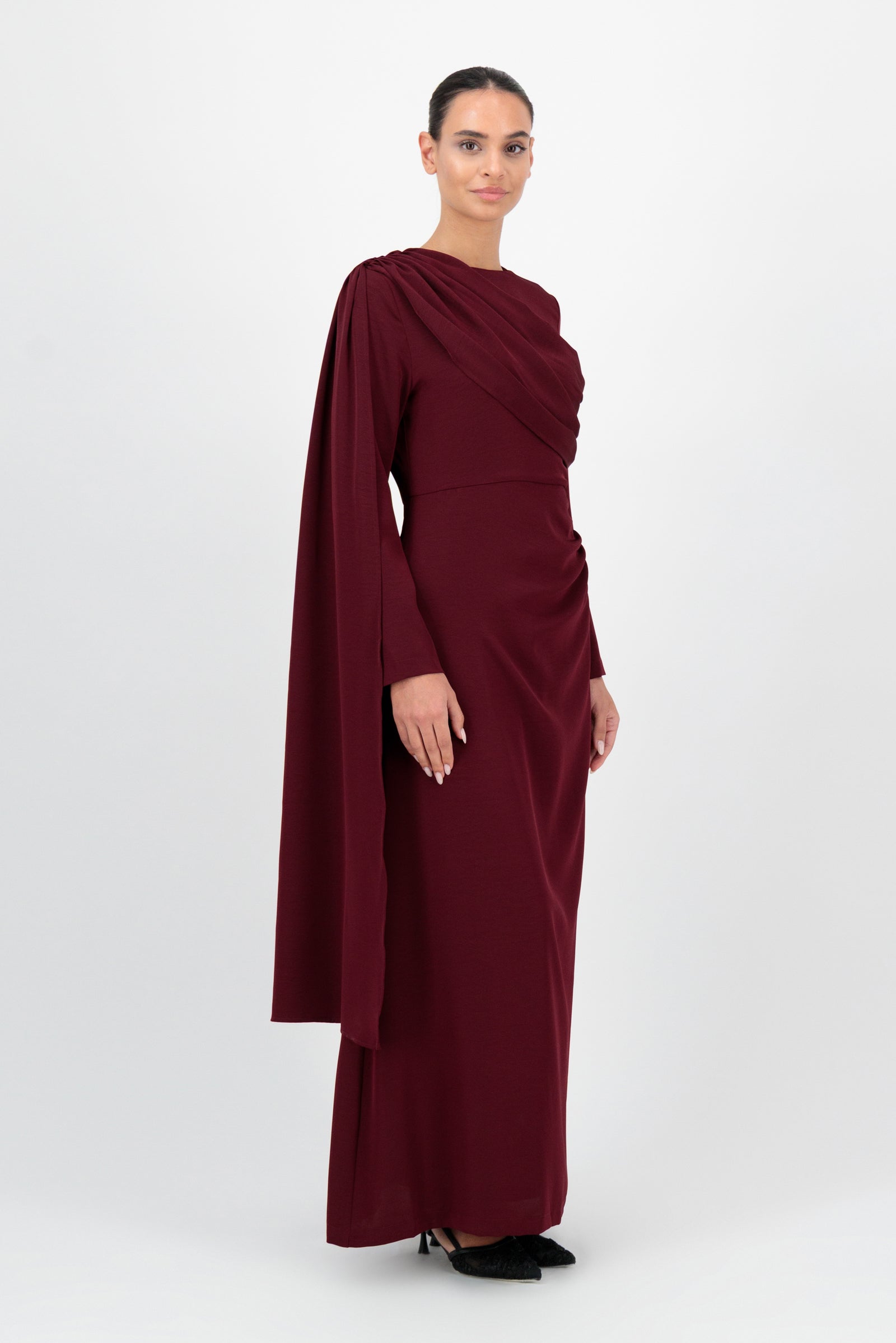 Side view of the FARES Ruched Shoulder Detail Dress in Karaz highlights the fluid silhouette of this deep-toned ruched dress.