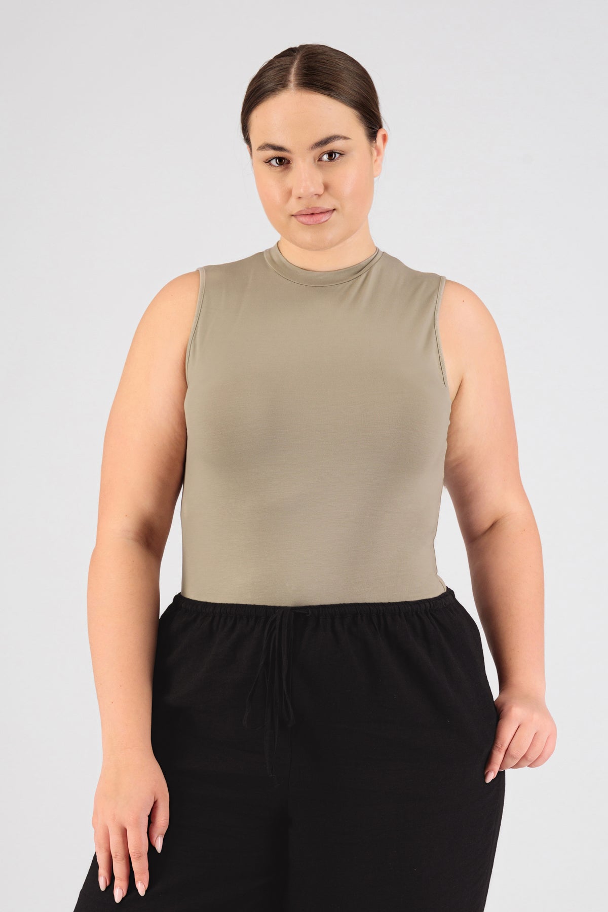 Colour description: Sand. The front of a model standing in FARES' sleeveless layer.