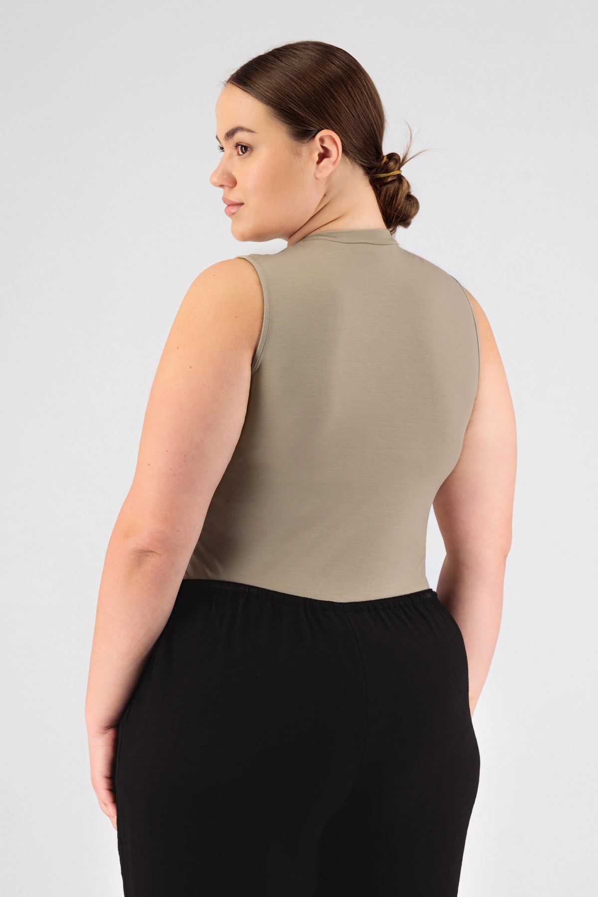 A girl wearing FARES' sleeveless layer is shown from the back while looking over her left shoulder. Colour description: Sand.