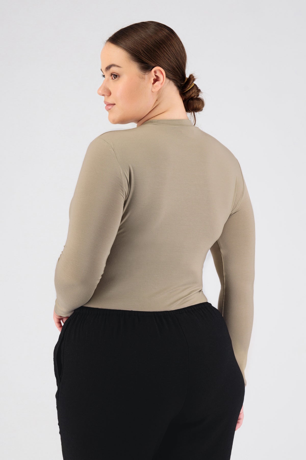 The girl wearing FARES' long sleeve layer is shown from the back while looking over her left shoulder. Colour description: Sand.
