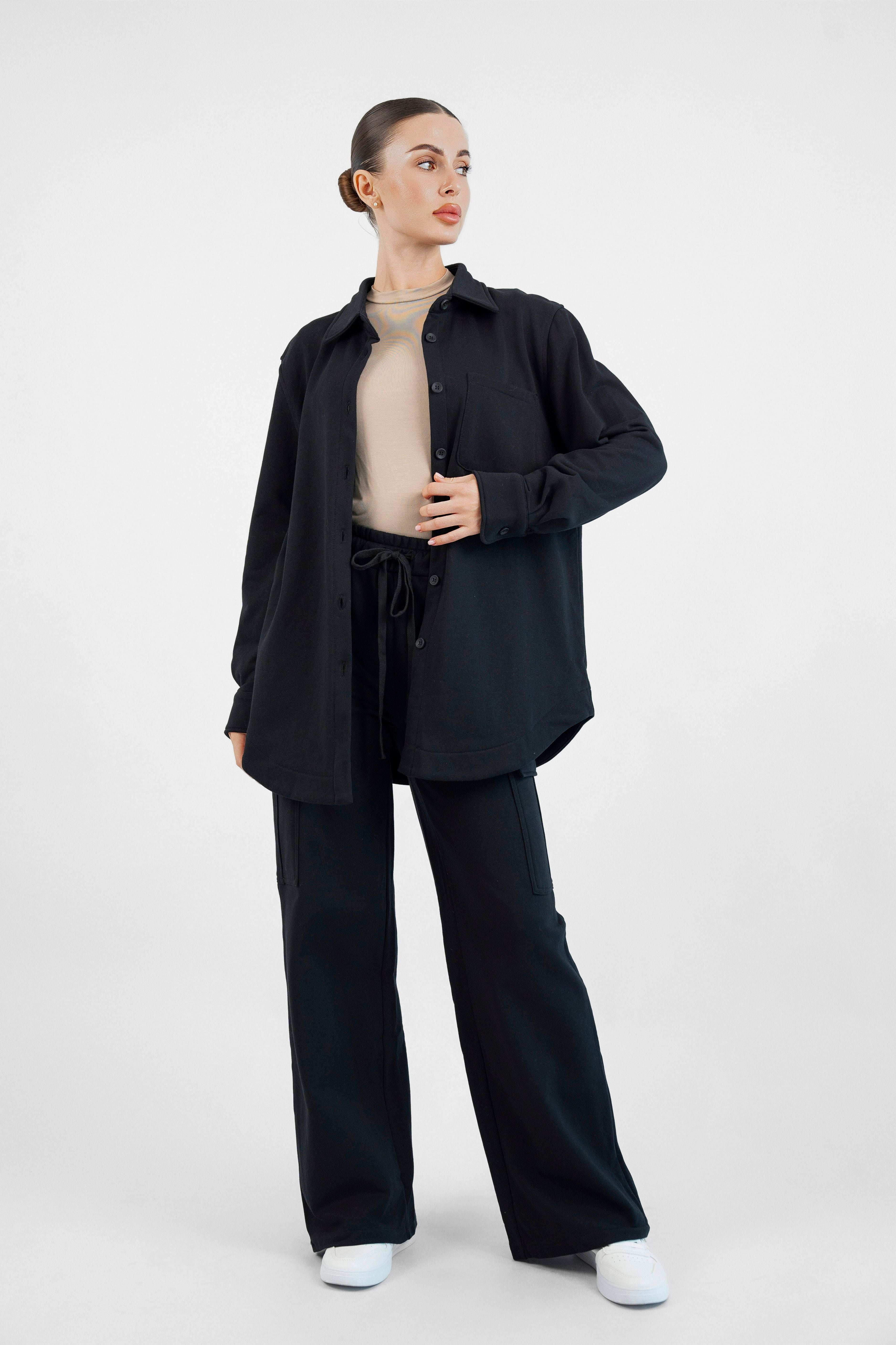 Colour: Black. A model is posing with her head turned right in an Oversized Cotton Shacket.