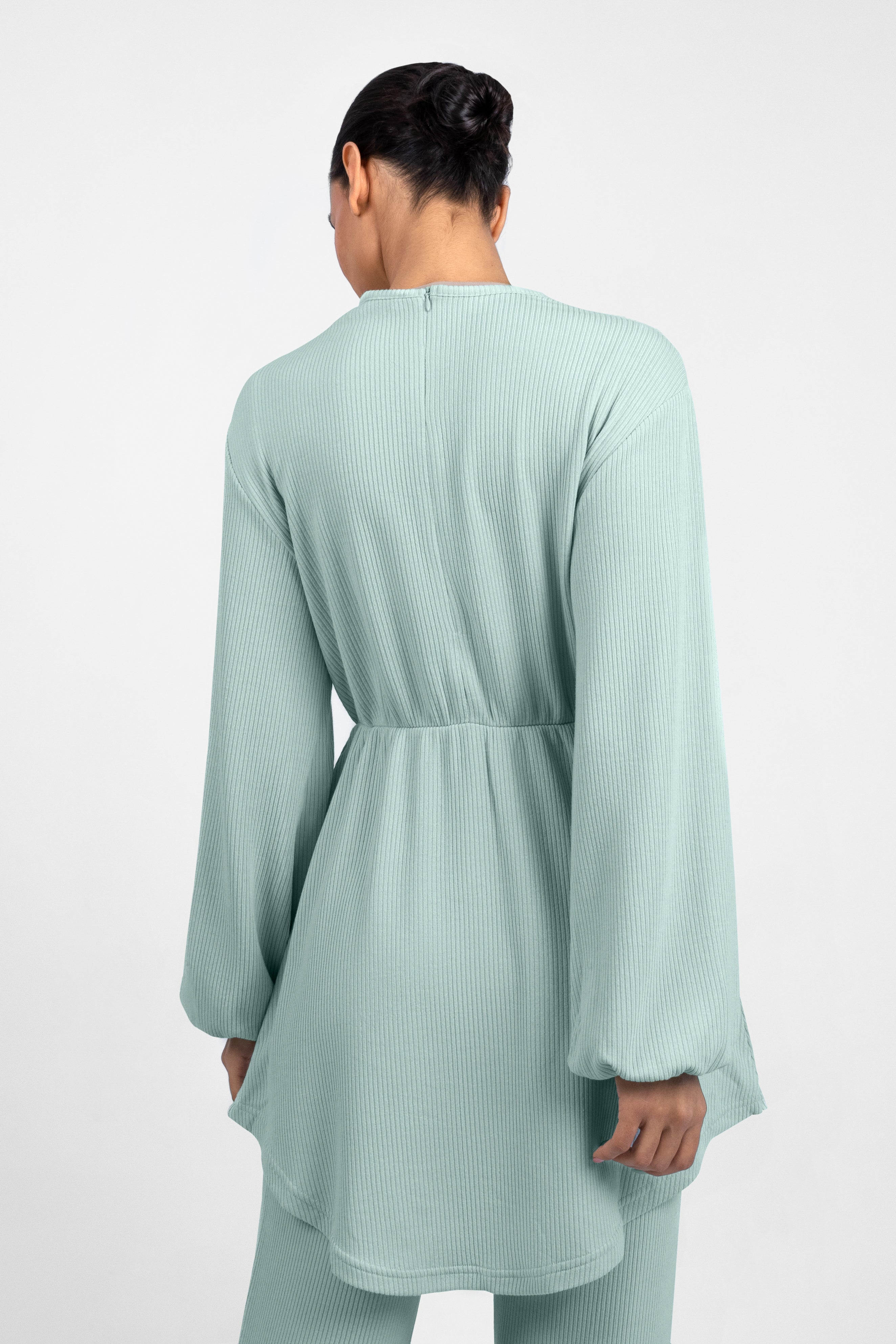 A back pose from a model in a Knit Peplum Top.	Colour: Icy: Blue