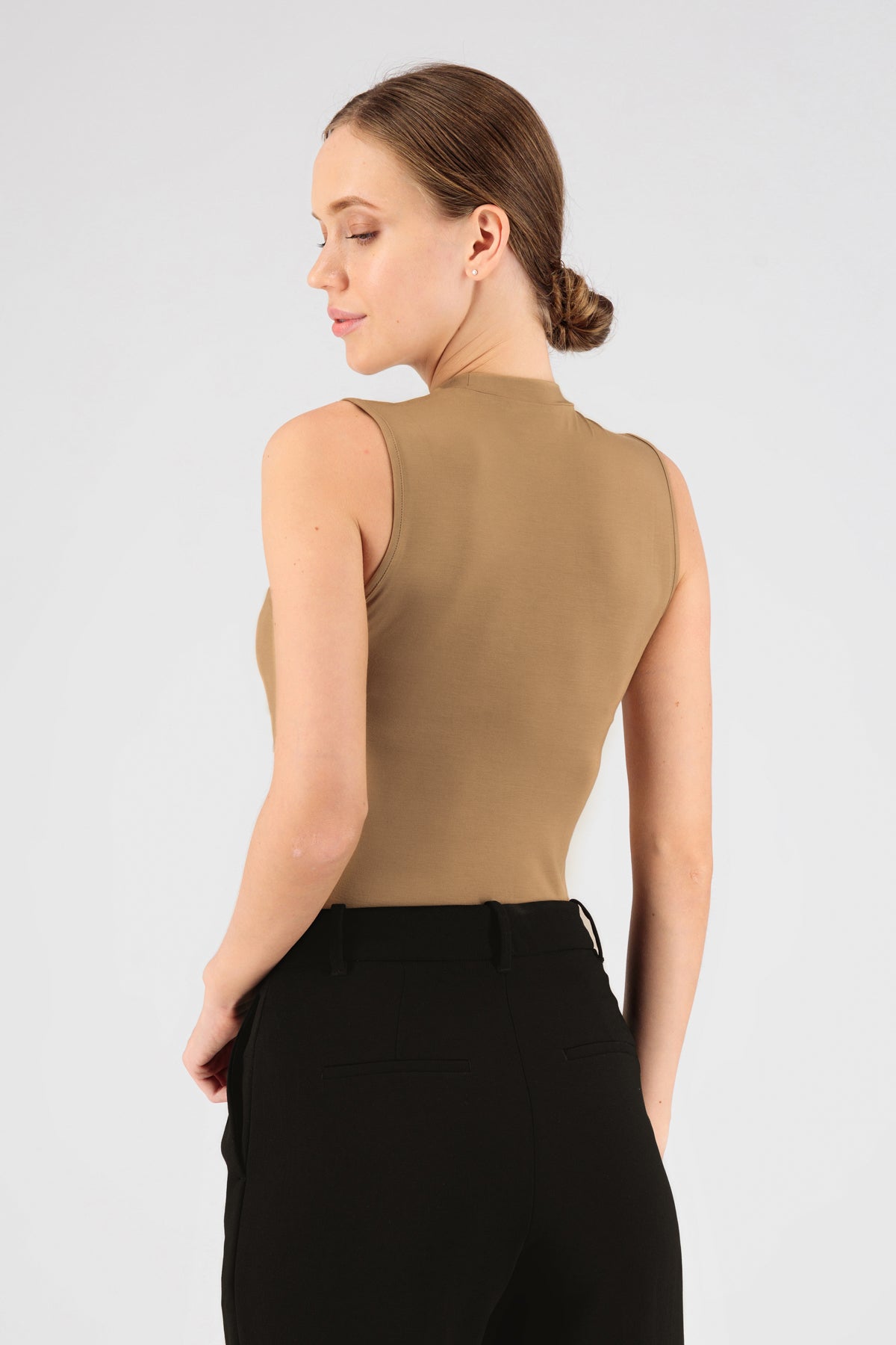 The girl wearing FARES' sleeveless layer is shown from the back. She is looking back over her left shoulder. Colour description: Tan.