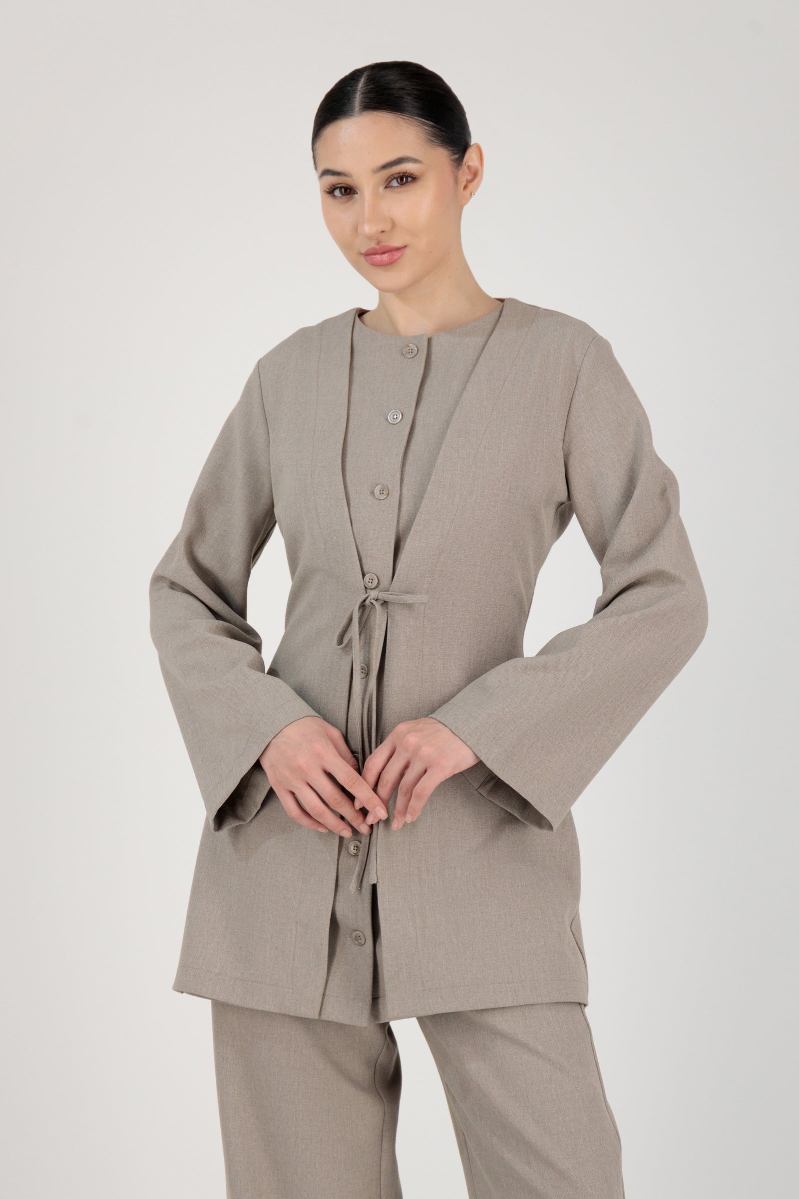 The FARES Tailored Button-Up Tunic in Stone styled closed, showing how this button-up tunic shapes the waist while remaining effortless.