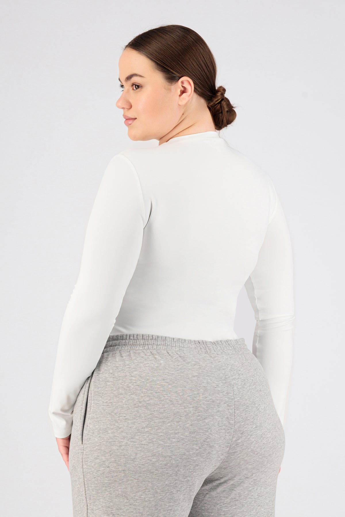A girl wearing FARES' long sleeve layer is shown from the back while looking over her left shoulder. Colour description: White.