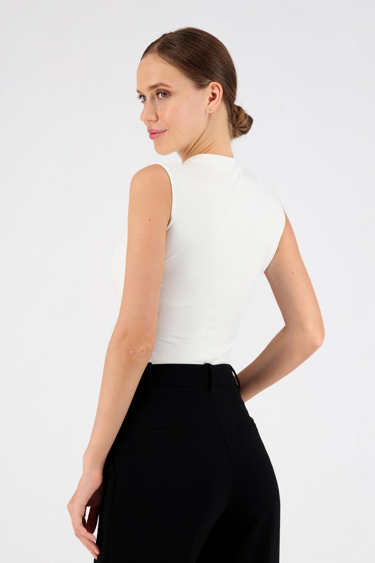 The girl wearing FARES' sleeveless layer is shown from the back. She is looking back over her left shoulder. Colour description: White.
