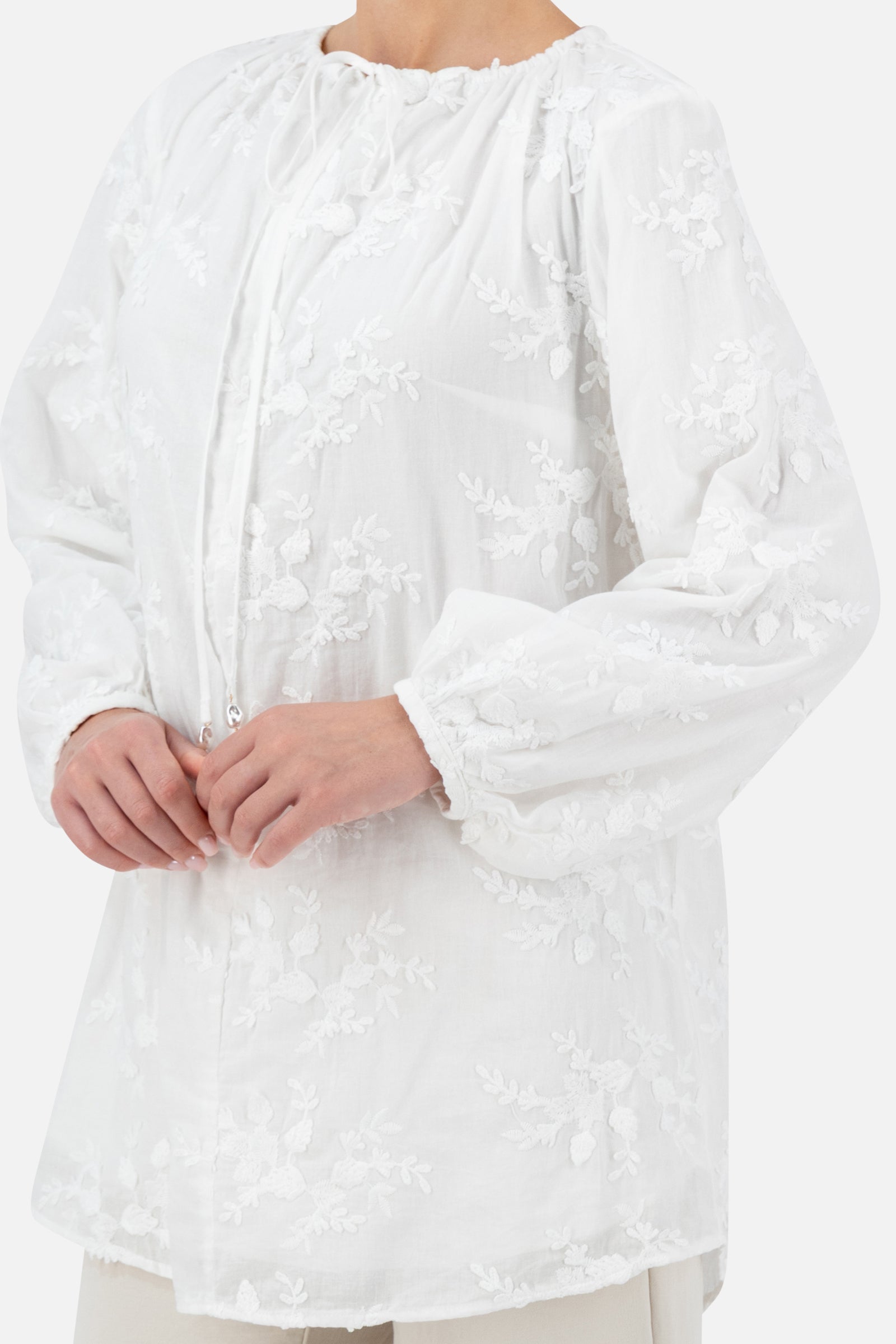 Close-up of the floral embroidery on the white blouse.