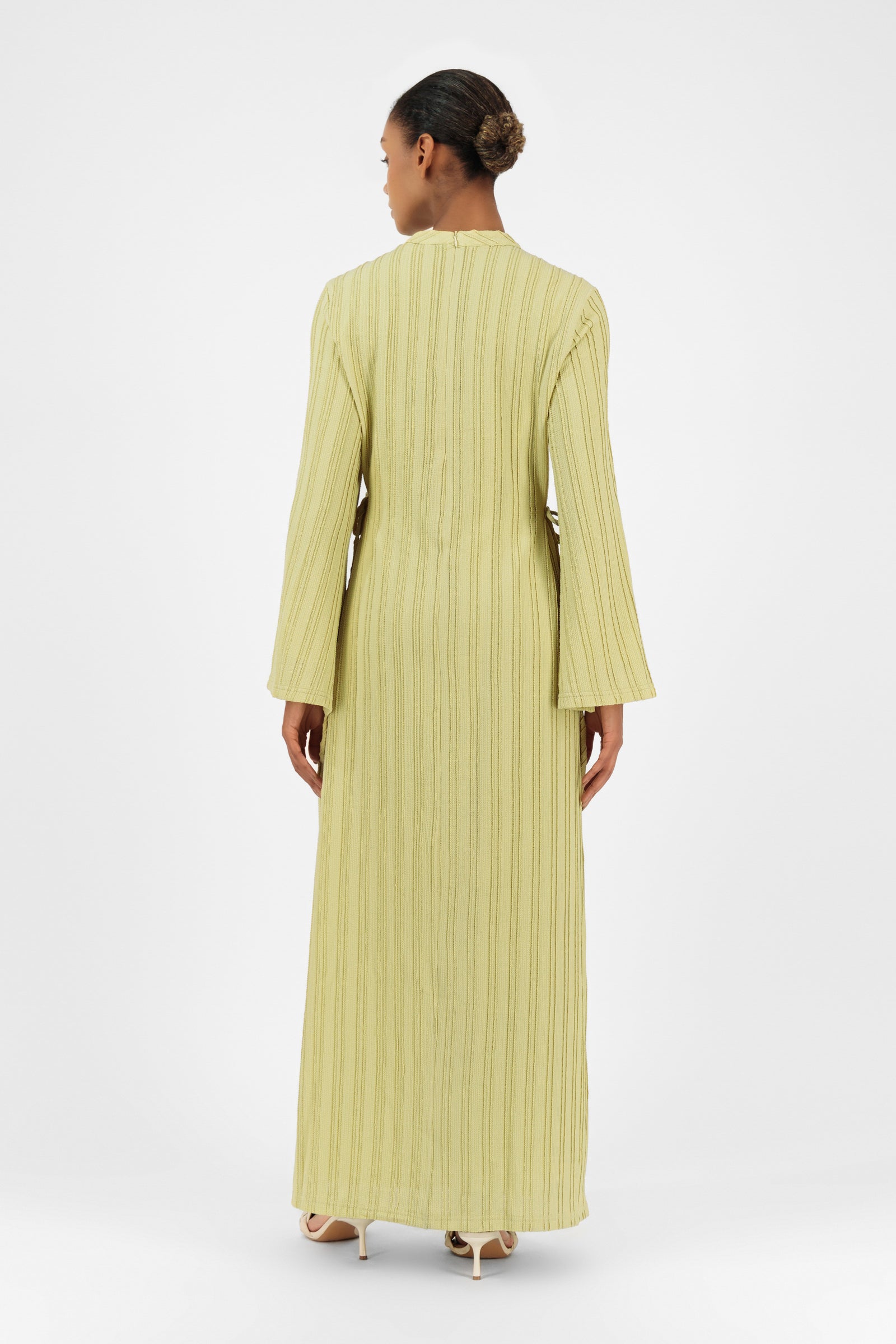 Back view of a woman wearing the lime FARES long sleeve maxi dress with elegant movement and wide sleeves.