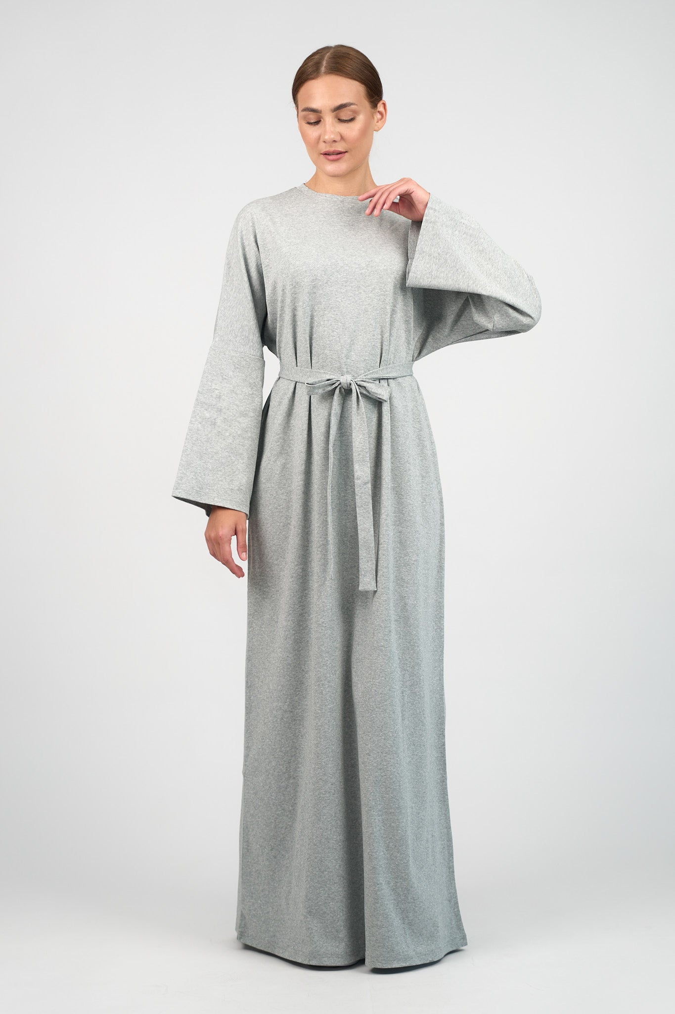 Colour: Grey Haze. A woman touchong the neck of the Cotton Maxi Dress she is wearing.