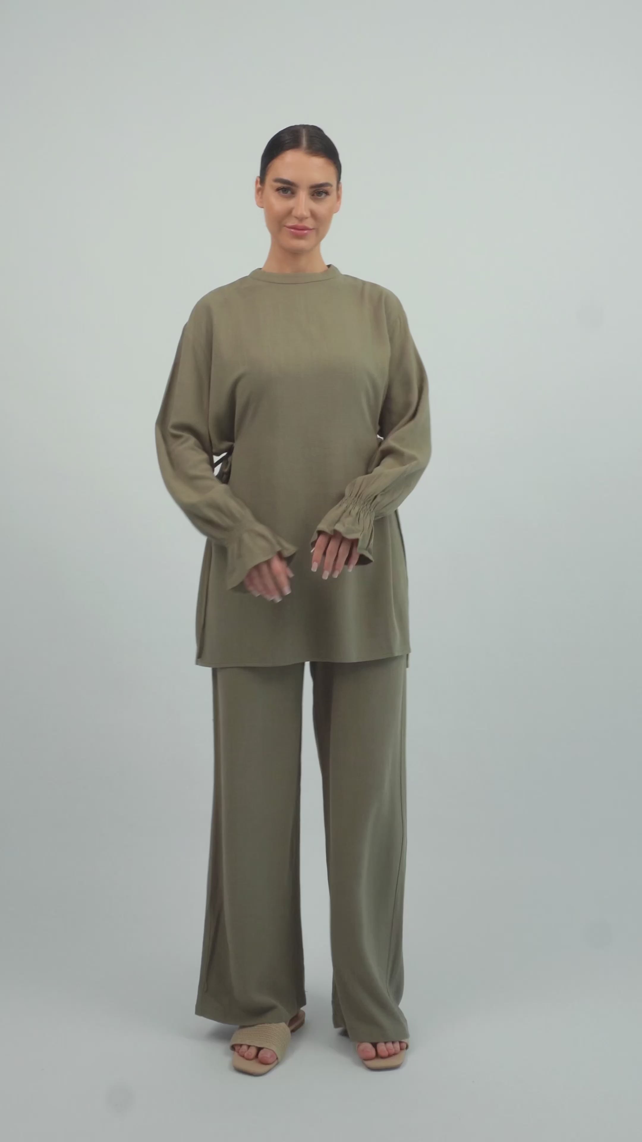 Model walking in the FARES Bow Detail Linen Blend Top in Olive Green, showing the lightweight movement and relaxed fit of the linen top.