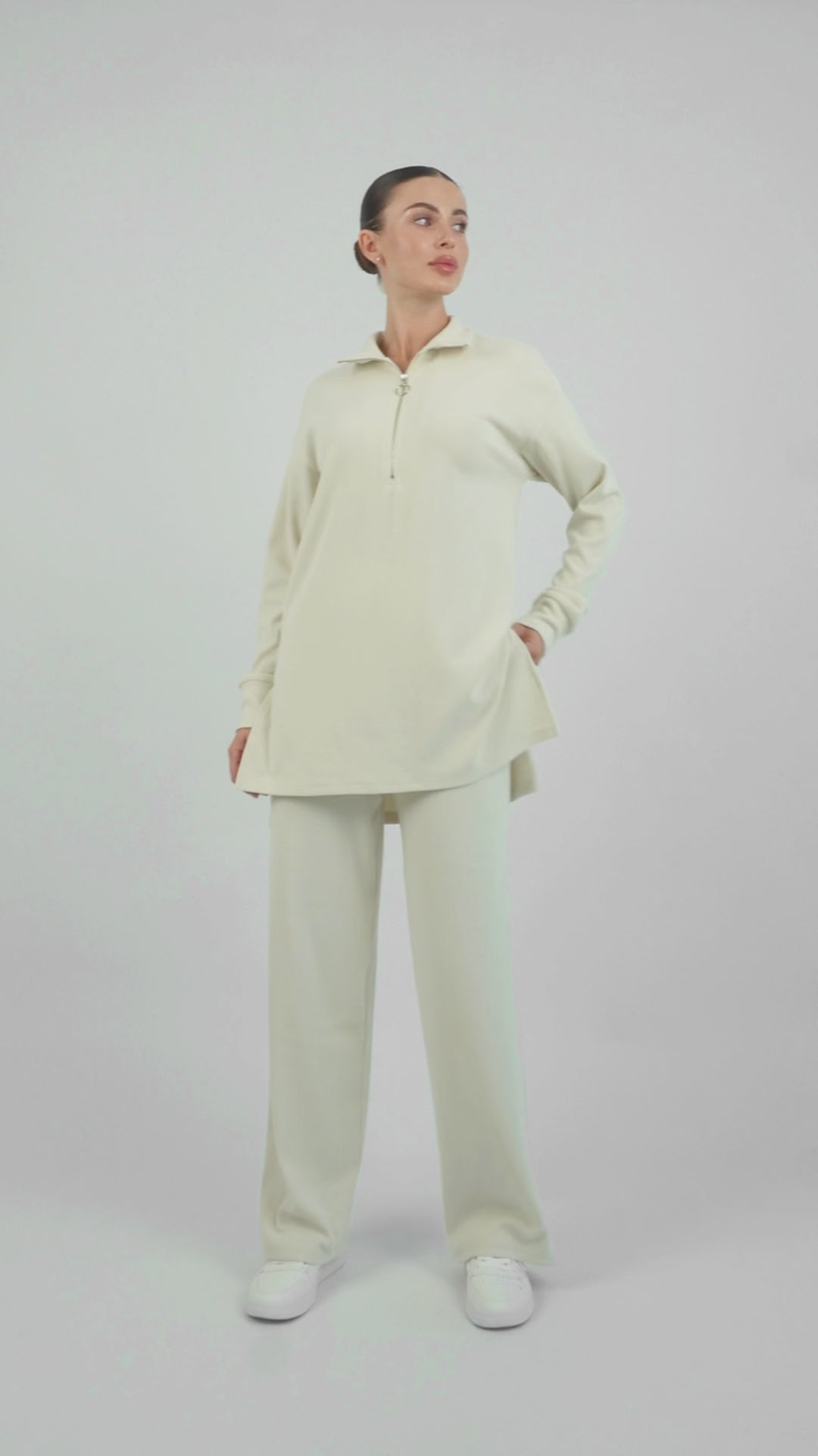 Colour description: Creamy Page. In the video the model is showing a couple of poses showcasing FARES' velour knit half zip sweater.