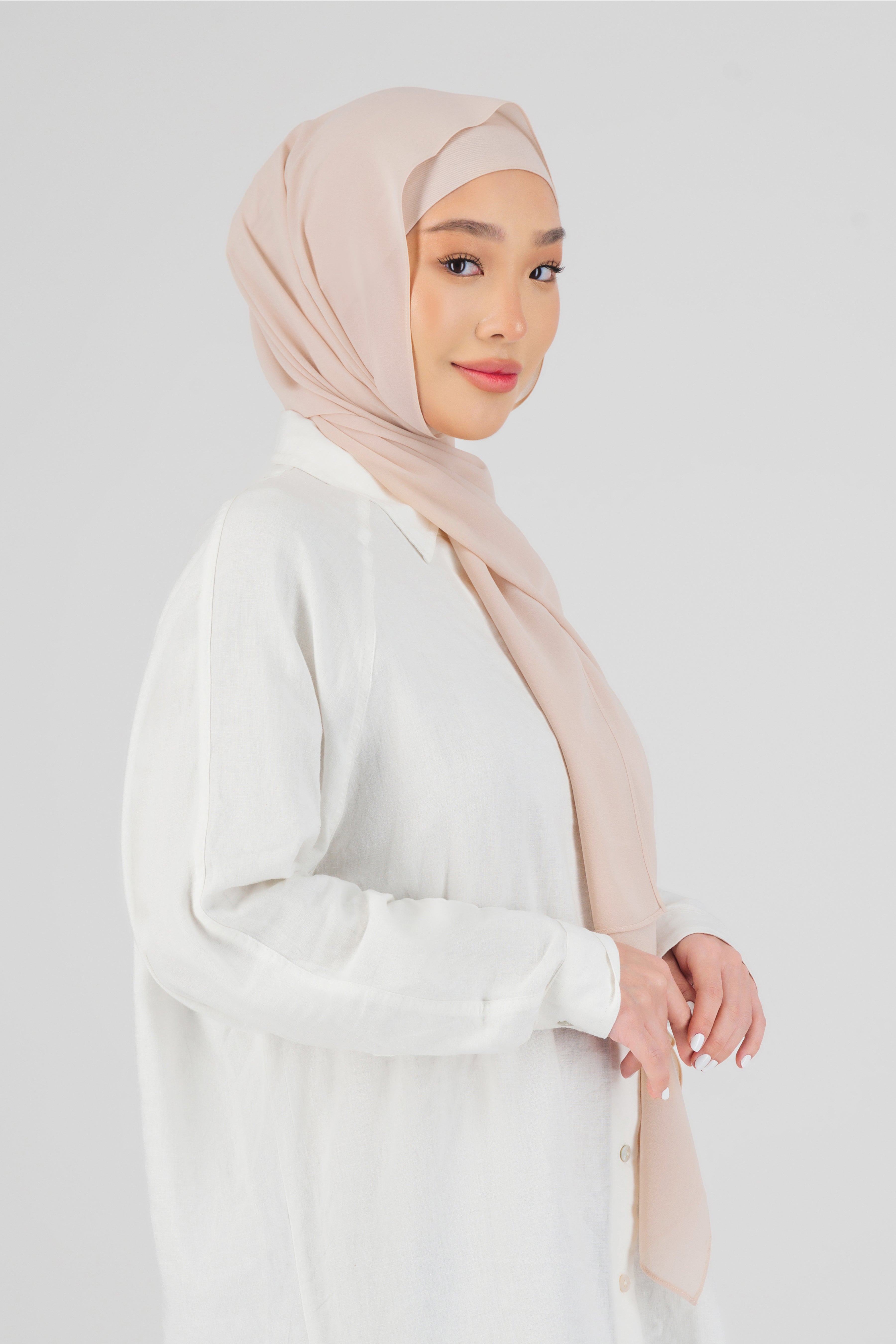 A woman wearing one of FARES's matching chiffon hijab sets. The model is turned to the right. Colour description: light pink.