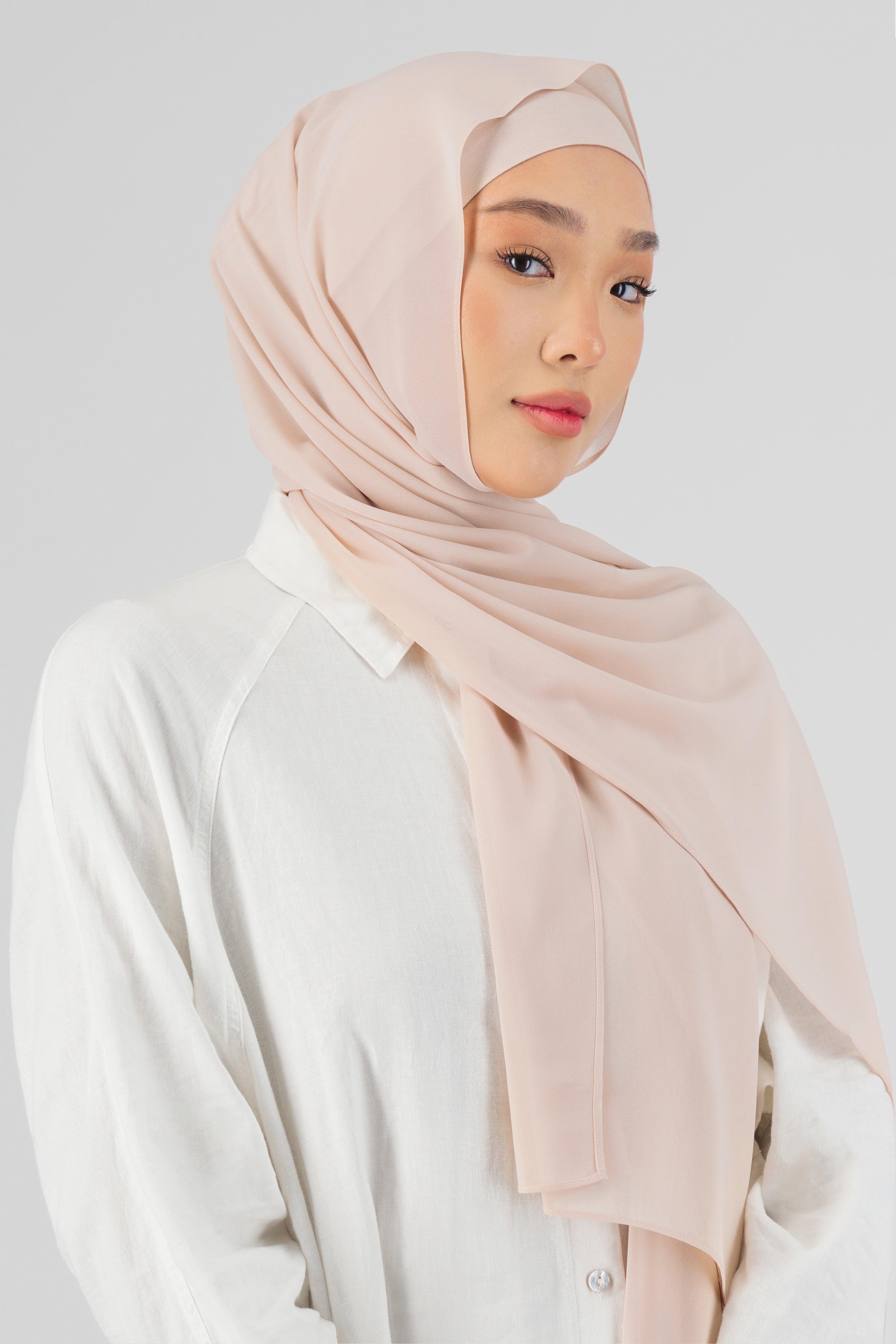 A close-up of a woman wearing one of FARES's matching chiffon hijab sets. The model is turned to the right. Colour description: light pink.