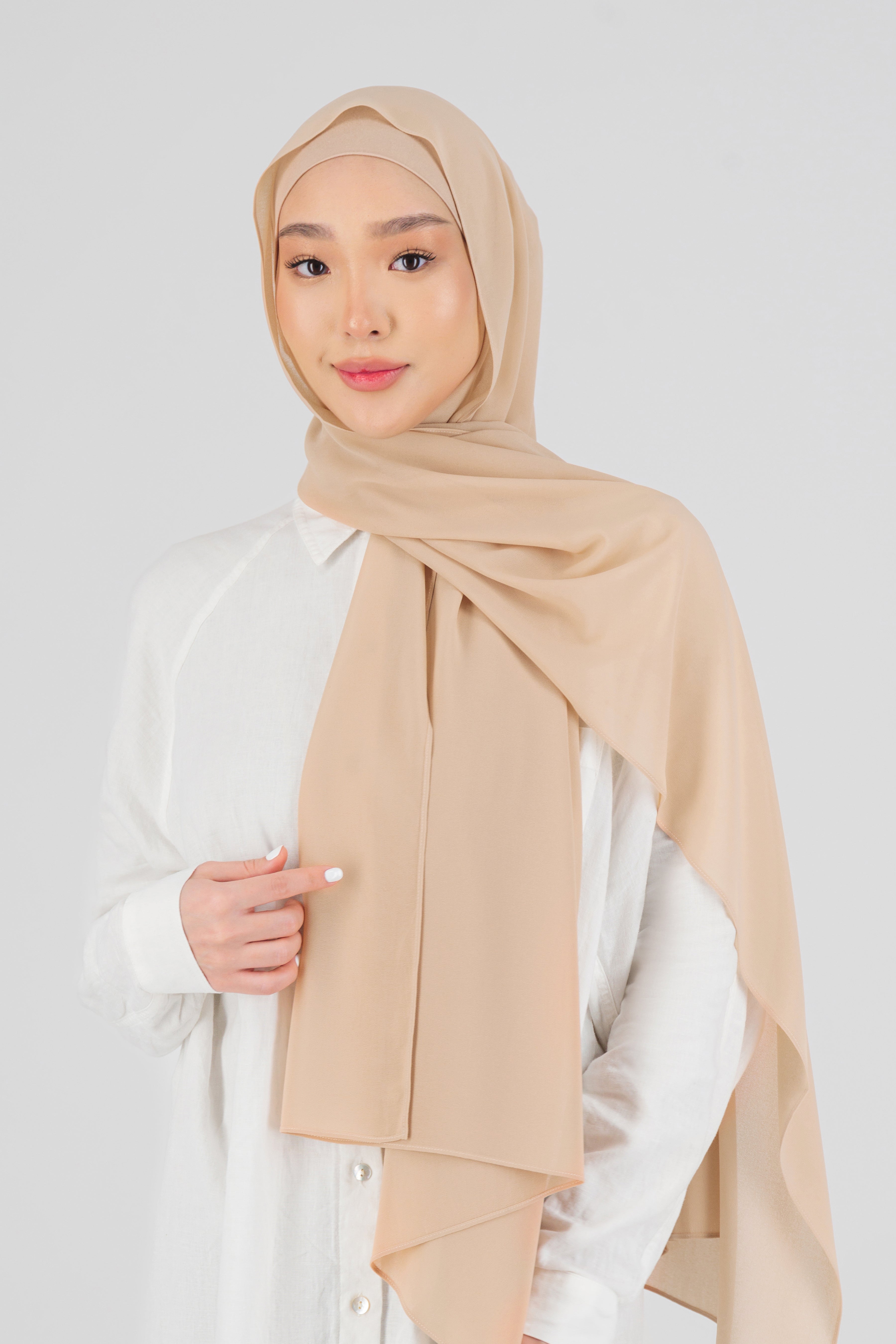 A woman wearing one of FARES's matching chiffon hijab sets. Colour description: light peach.
