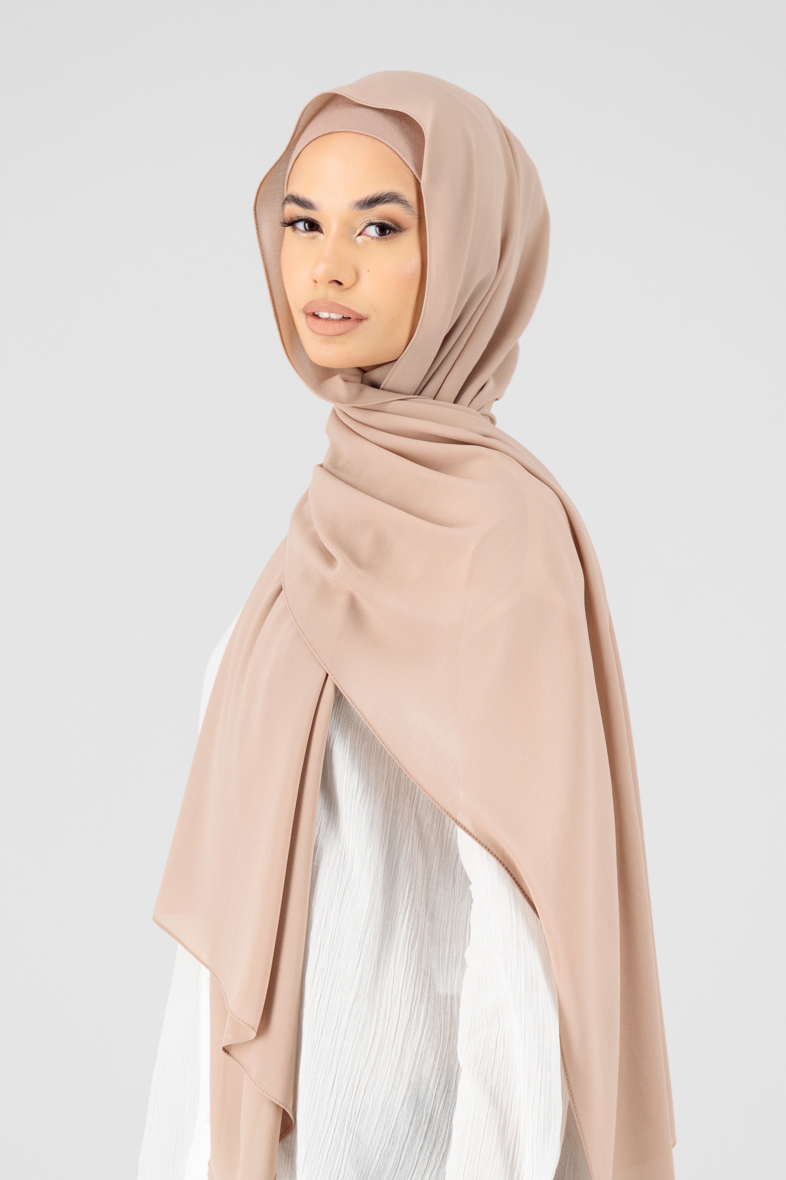 A woman wearing a matching chiffon hijab set from FARES. Colour description: muted pink beige. The model is turned to the left.