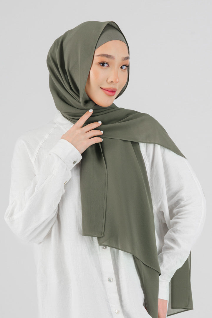 A woman wearing a matching chiffon hijab set from FARES. Colour description: medium green.