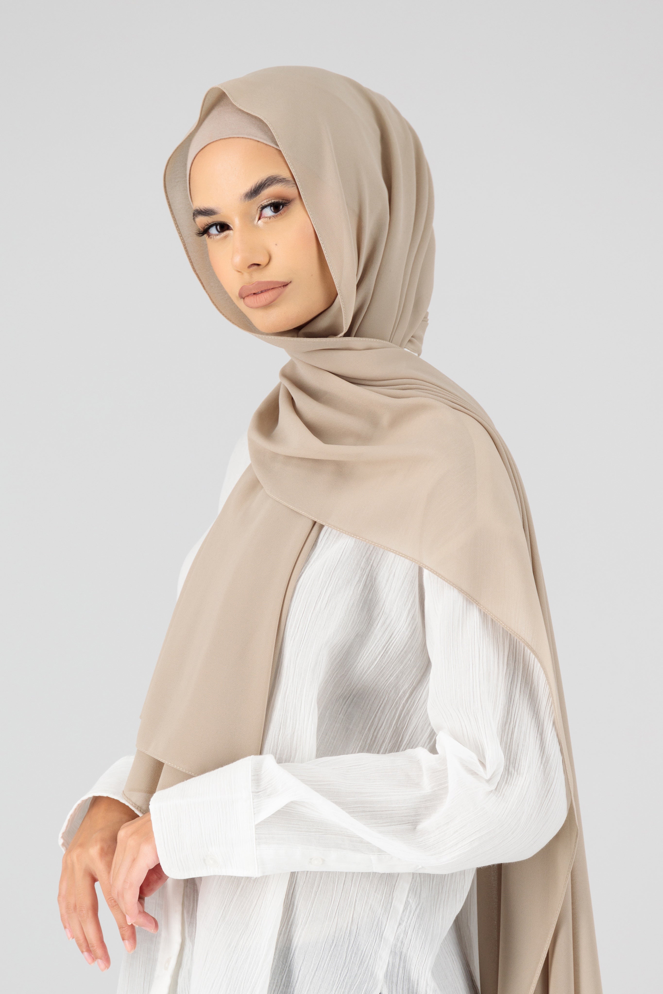 A woman wearing a matching chiffon hijab set from FARES. Colour description: light beige. The model is turned to the left.