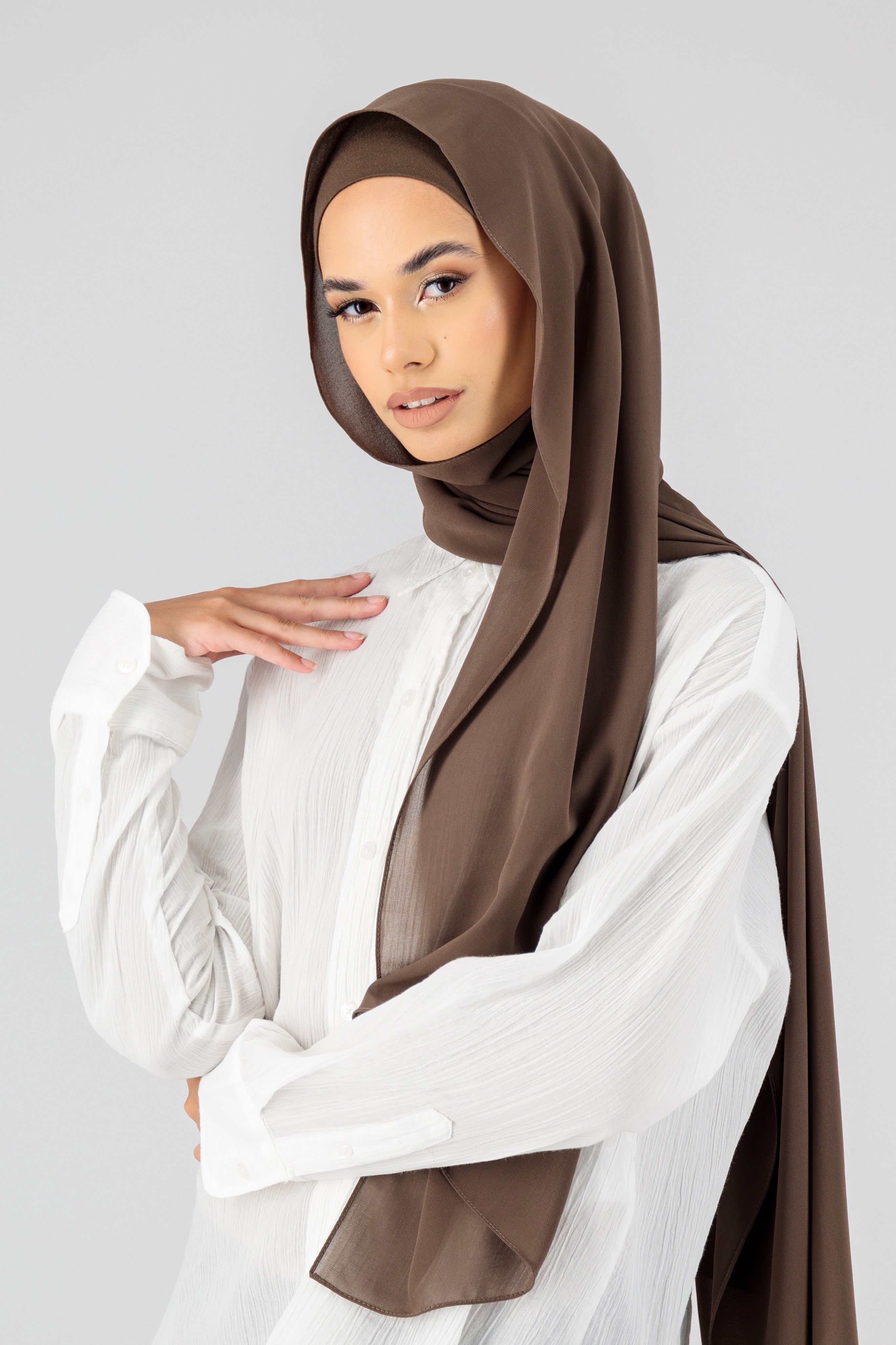 A woman wearing one of FARES's matching chiffon hijab sets. Colour description: cool dark brown.