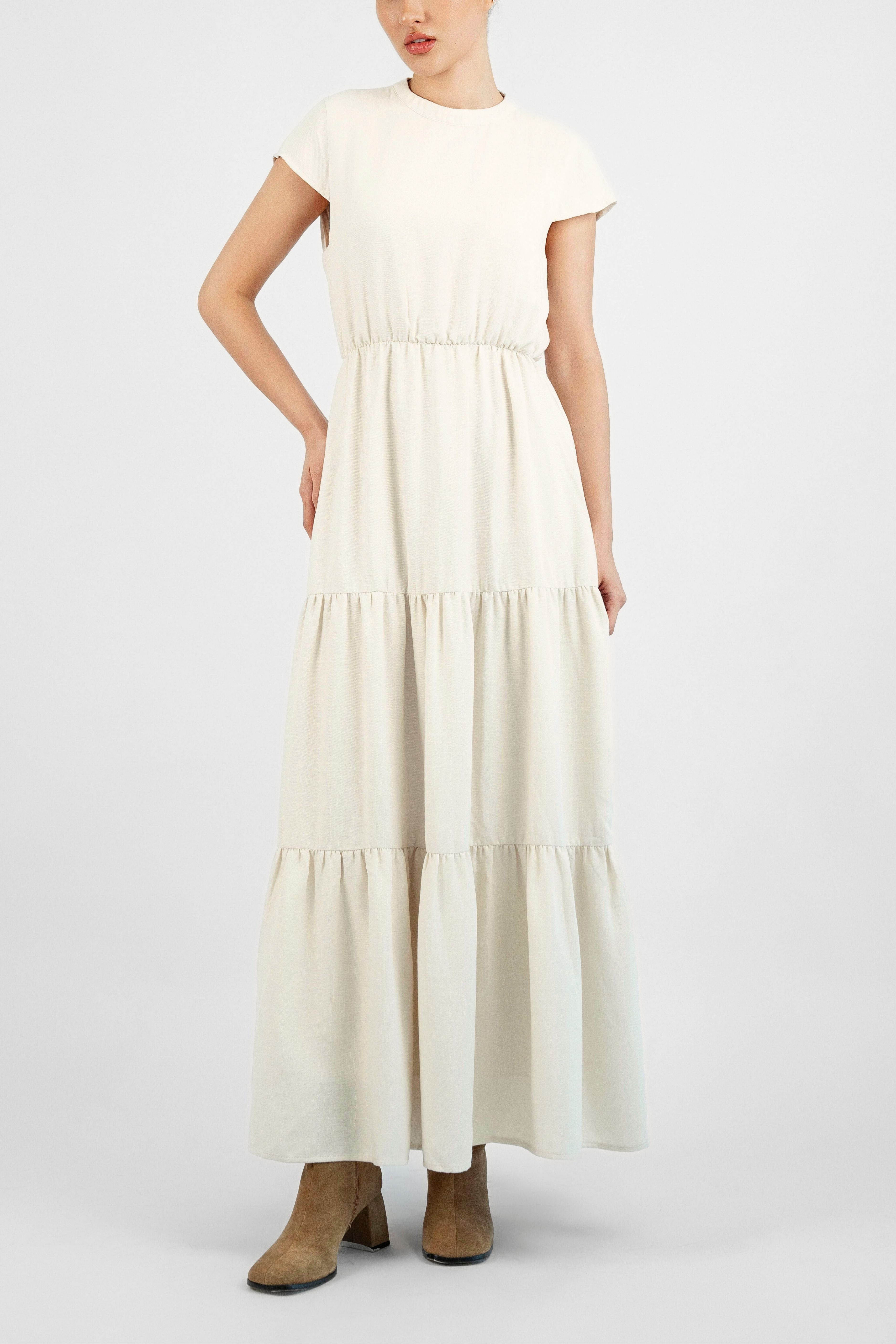 The girl is facing the camera in a tiered dress. Colour description: Cream.