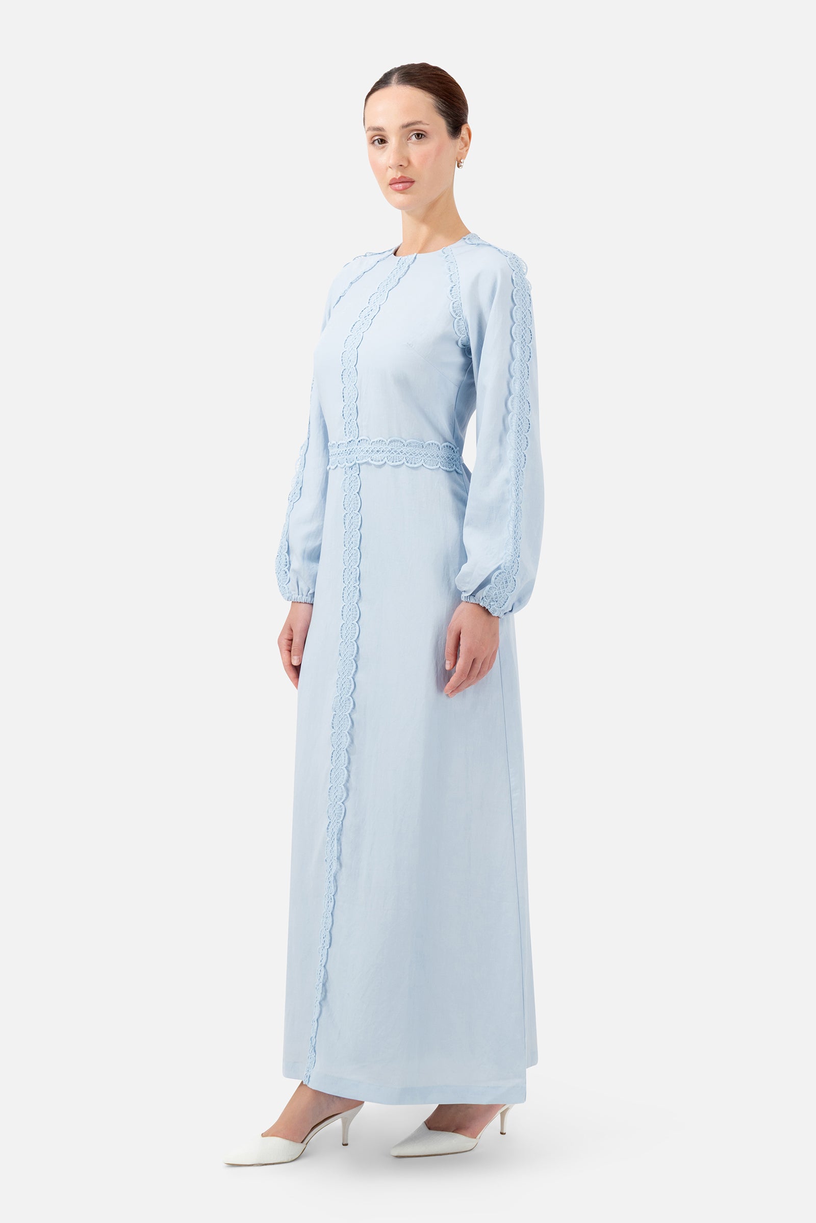 Woman standing in the Bluebell Crochet Trim Maxi Dress with long sleeves and a graceful drape.