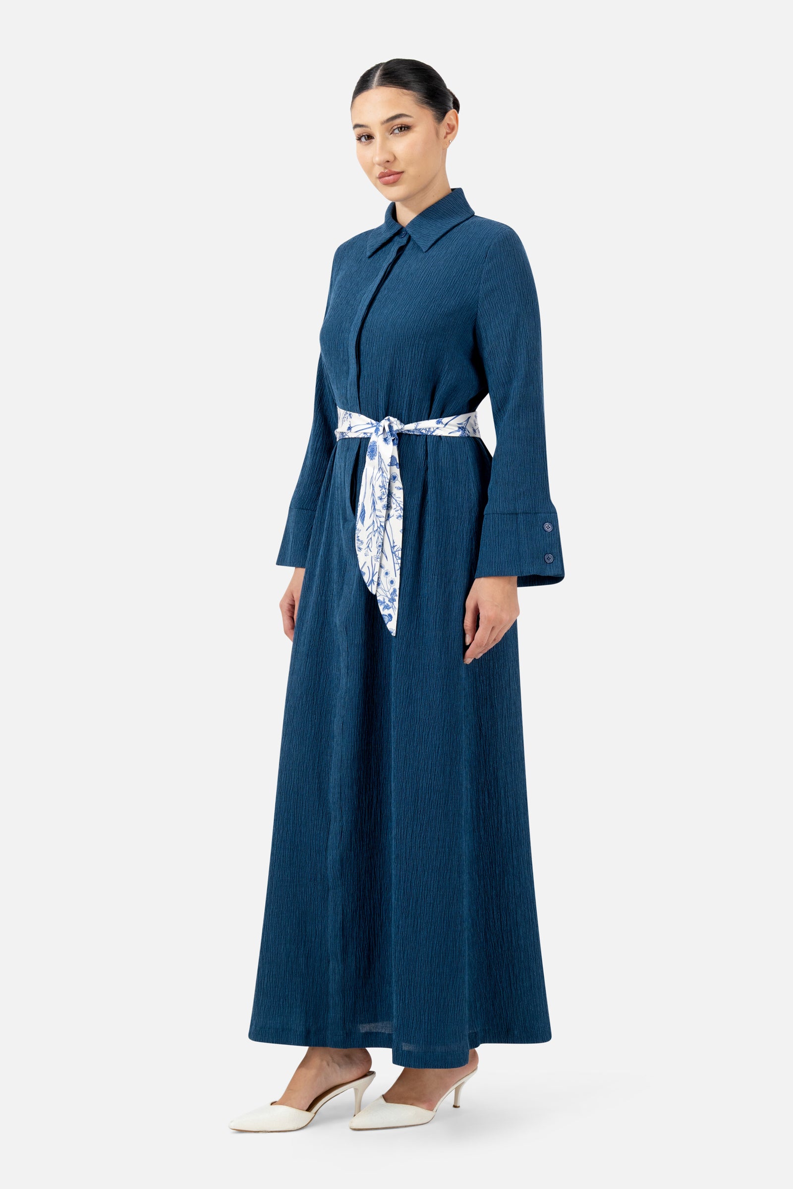 Woman standing in the Indigo Printed Satin Belt Dress with long sleeves and a printed waist belt.
