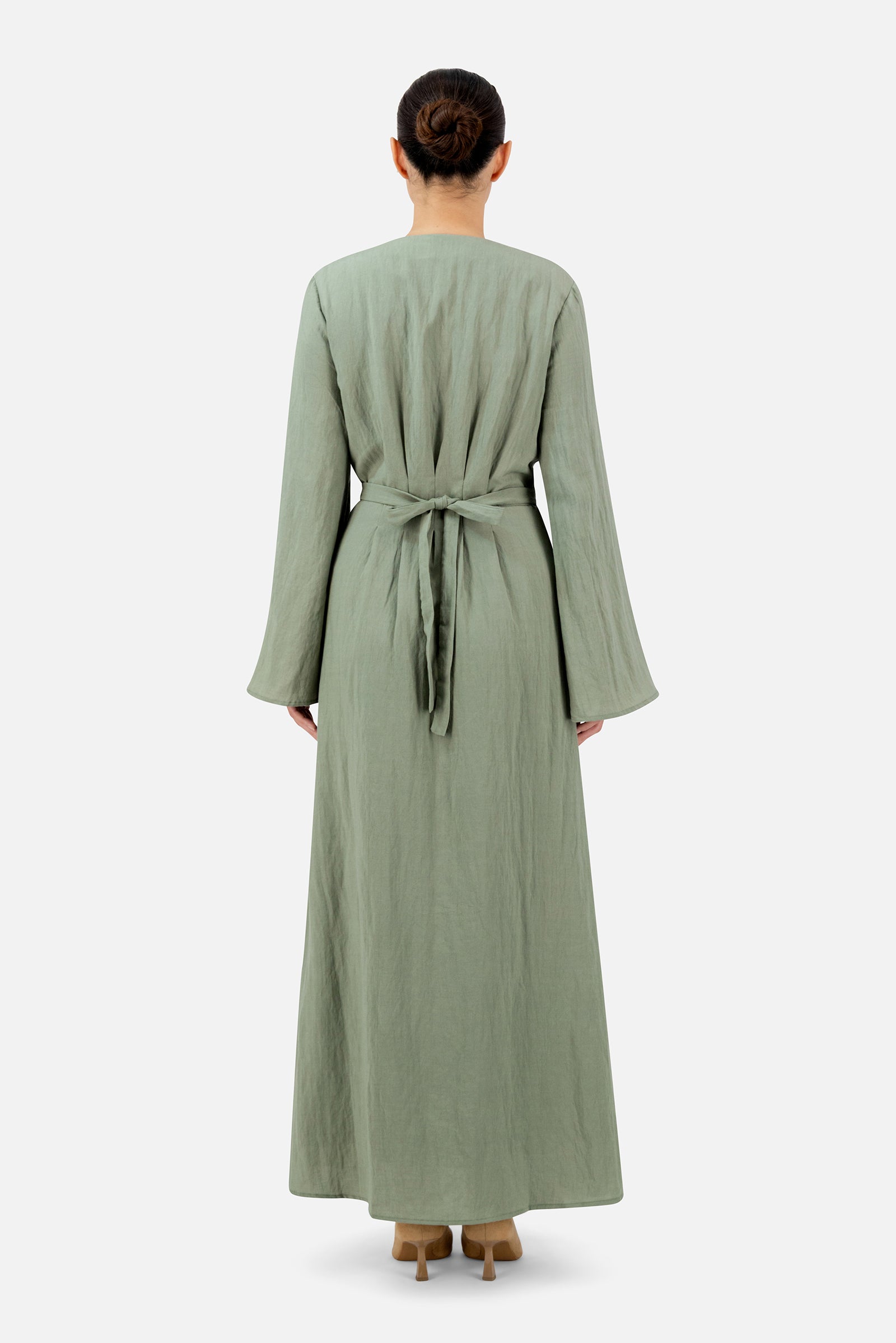 Back view of a woman wearing the clover FARES maxi dress showcasing the adjustable waist tie and flowing skirt shape.