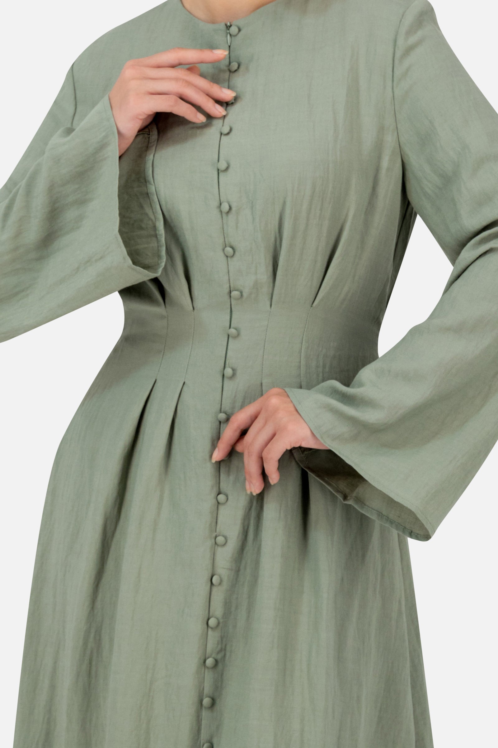 Detailed view of the clover FARES maxi dress highlighting the pleated waist design decorative buttons and flowing sleeve details.