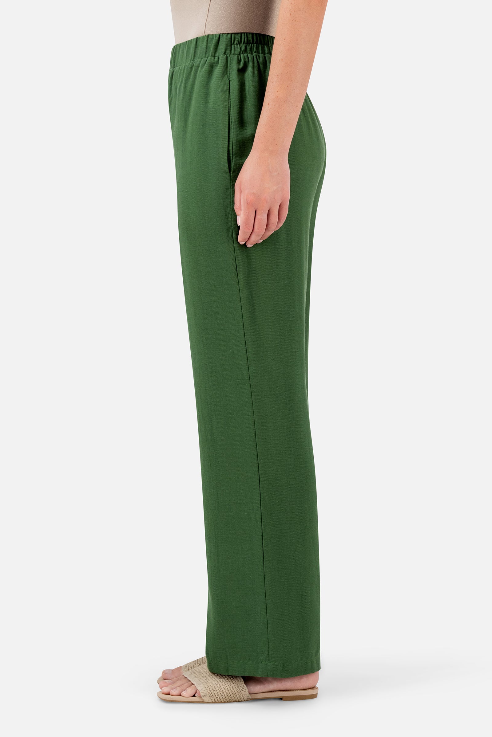 FARES Relaxed Fit Pants in Evergreen shown from the side, featuring a loose full-length shape and softly draped fabric.