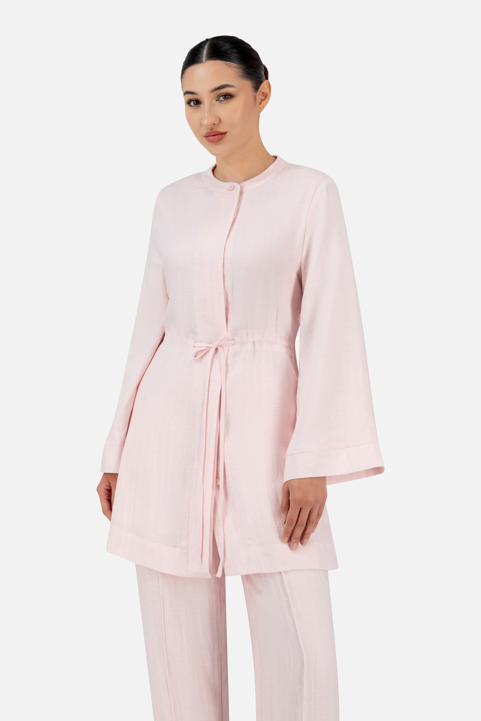Model standing in the FARES Drawstring Waist Button Up in Strawberry Cream featuring a soft tunic silhouette with elegant waist detailing.