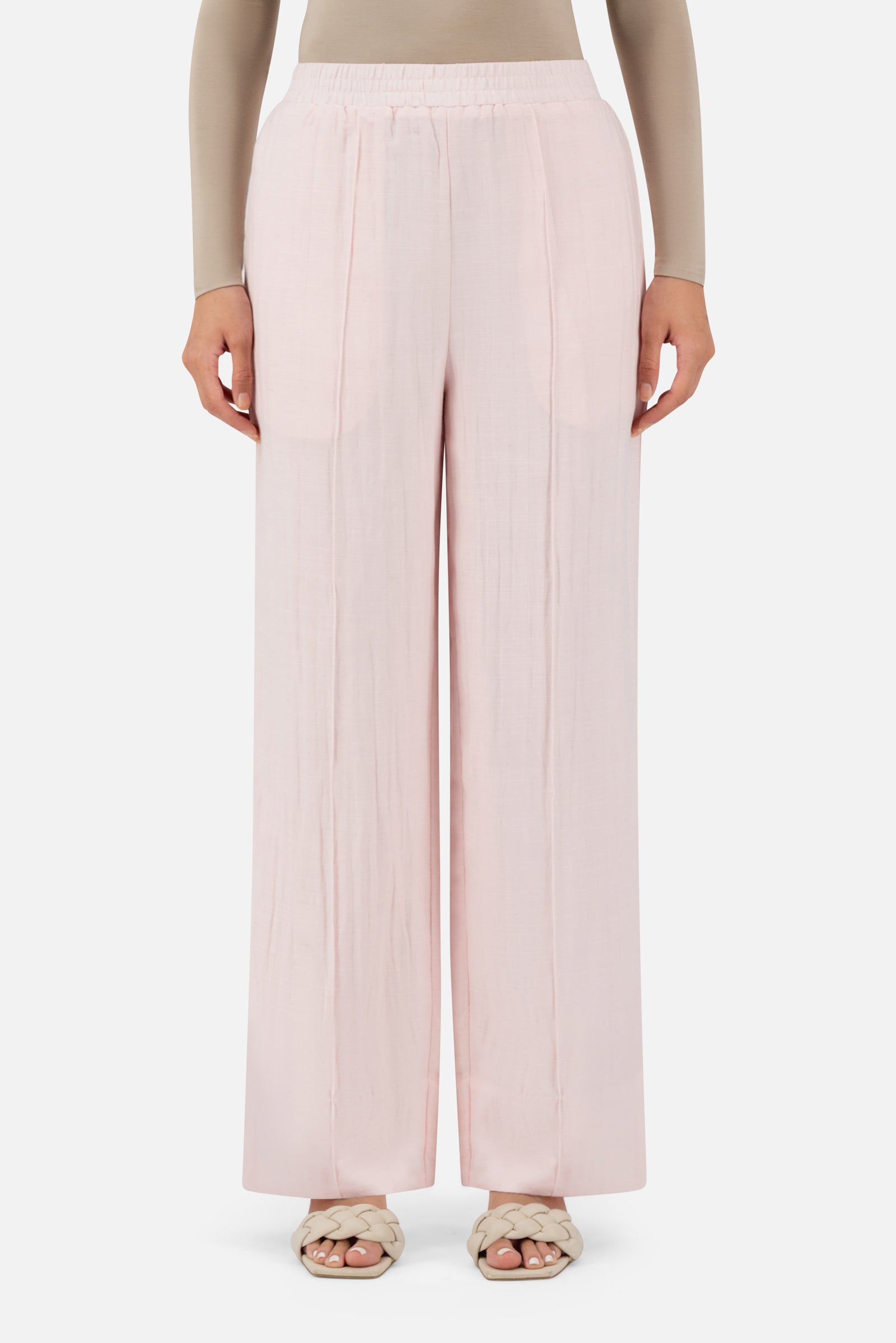 Model standing in the FARES Straight Leg Flowy Pants in Strawberry Cream featuring soft linen pants with an elegant flowing silhouette.