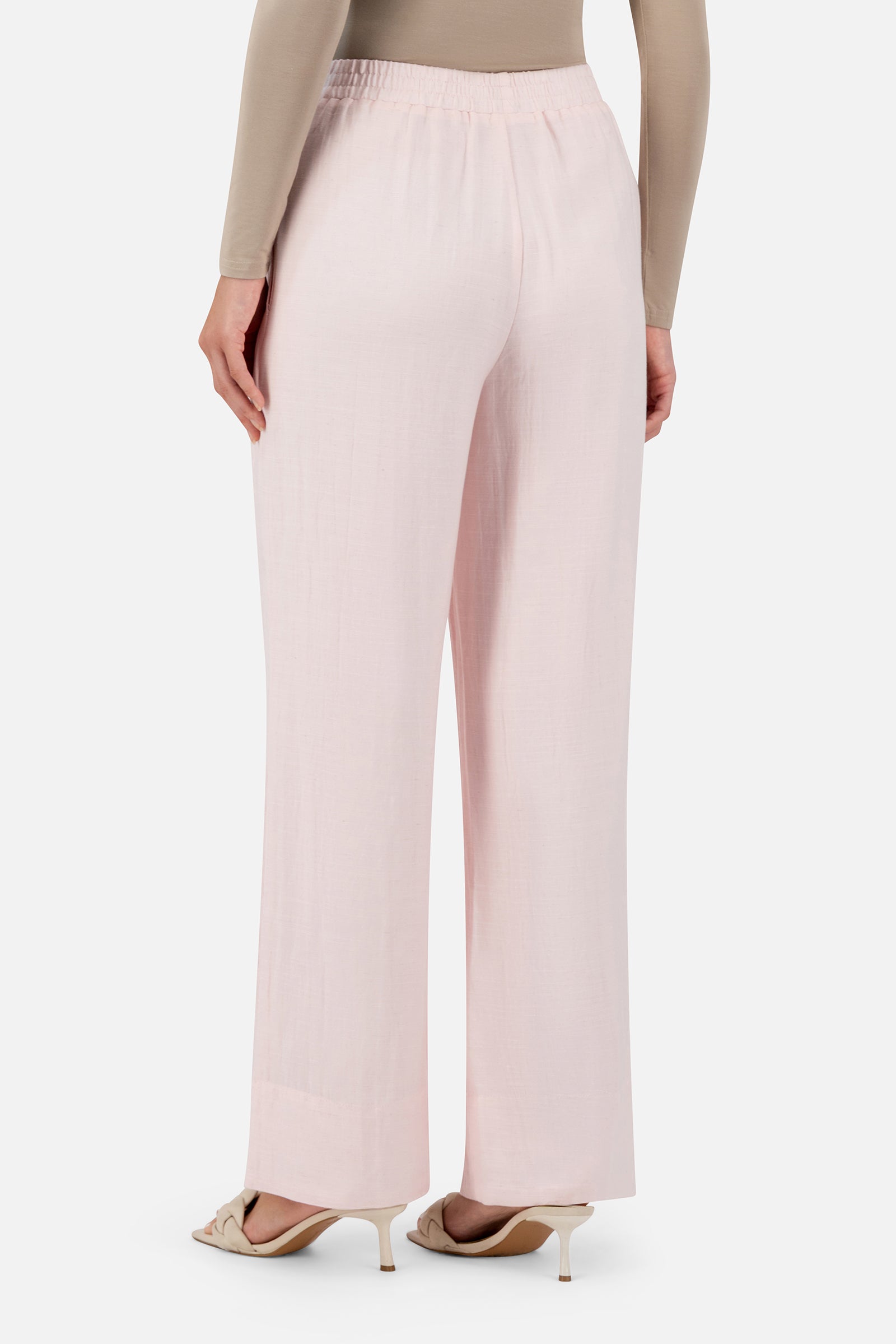 Back view of a woman wearing the Strawberry Cream FARES straight leg pants showcasing the relaxed fit and clean tailored finish.