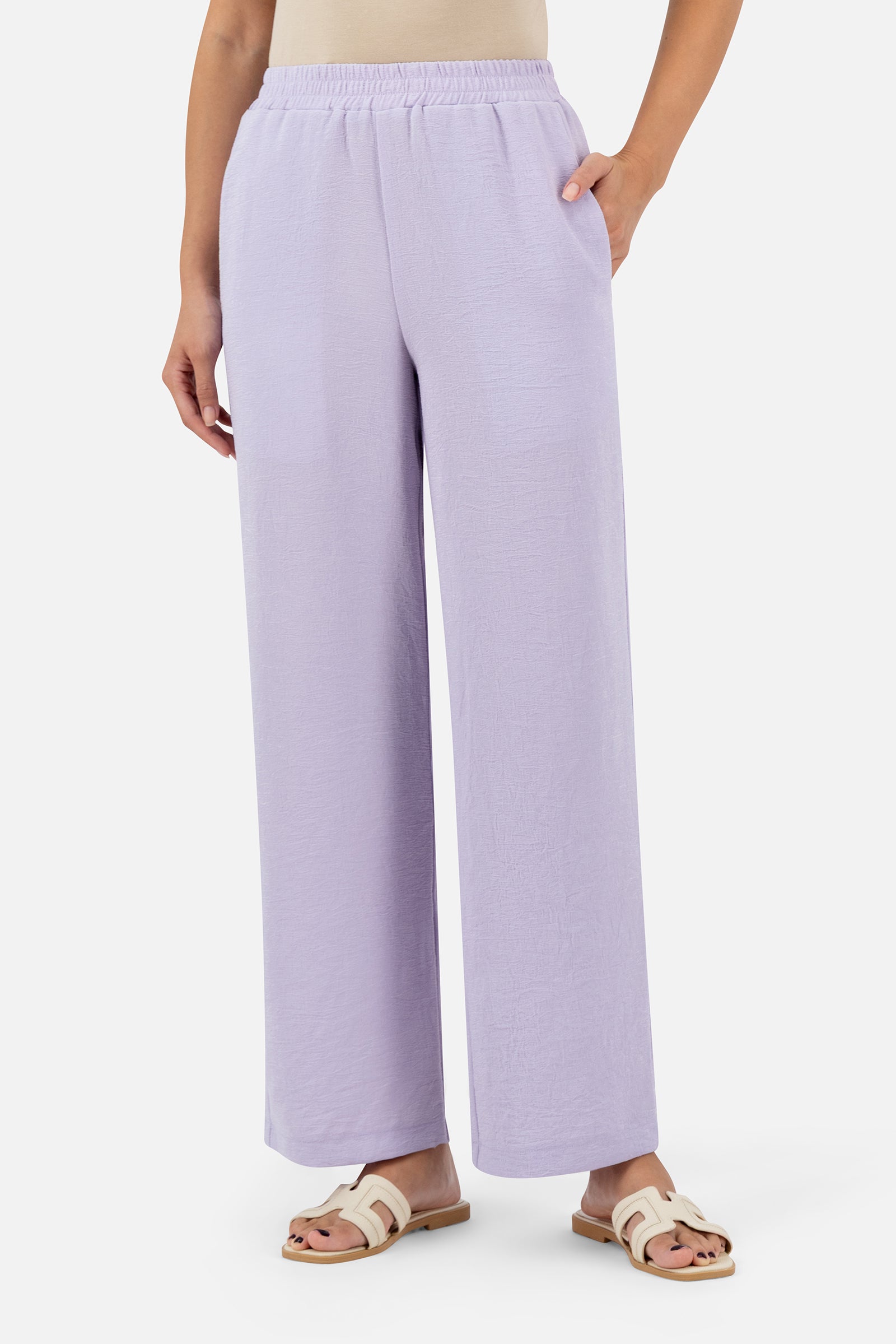 Woman standing in the Lilac relaxed fit pants paired with the matching asymmetric tunic.