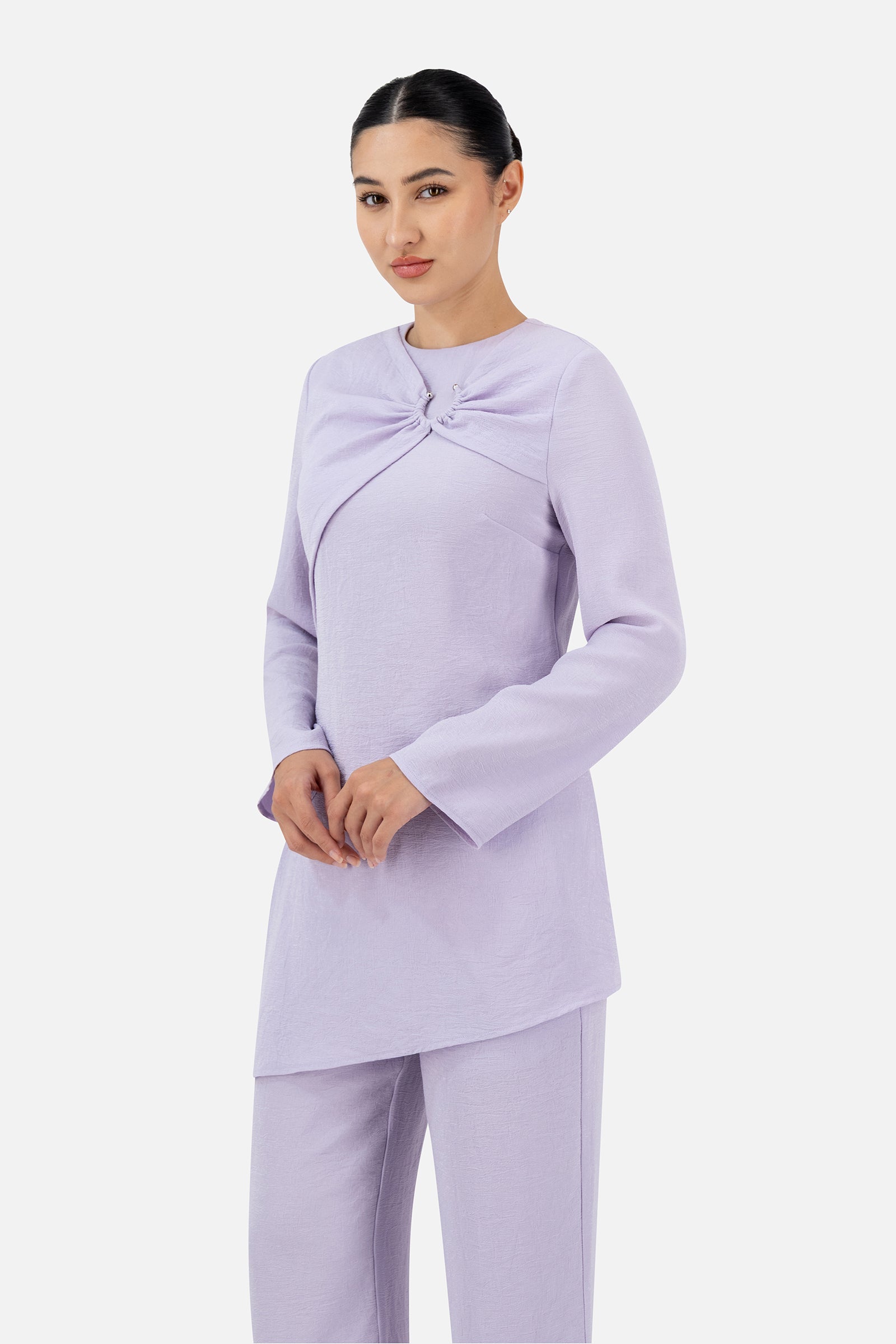 Woman standing in the Lilac asymmetric tunic paired with matching relaxed fit pants.