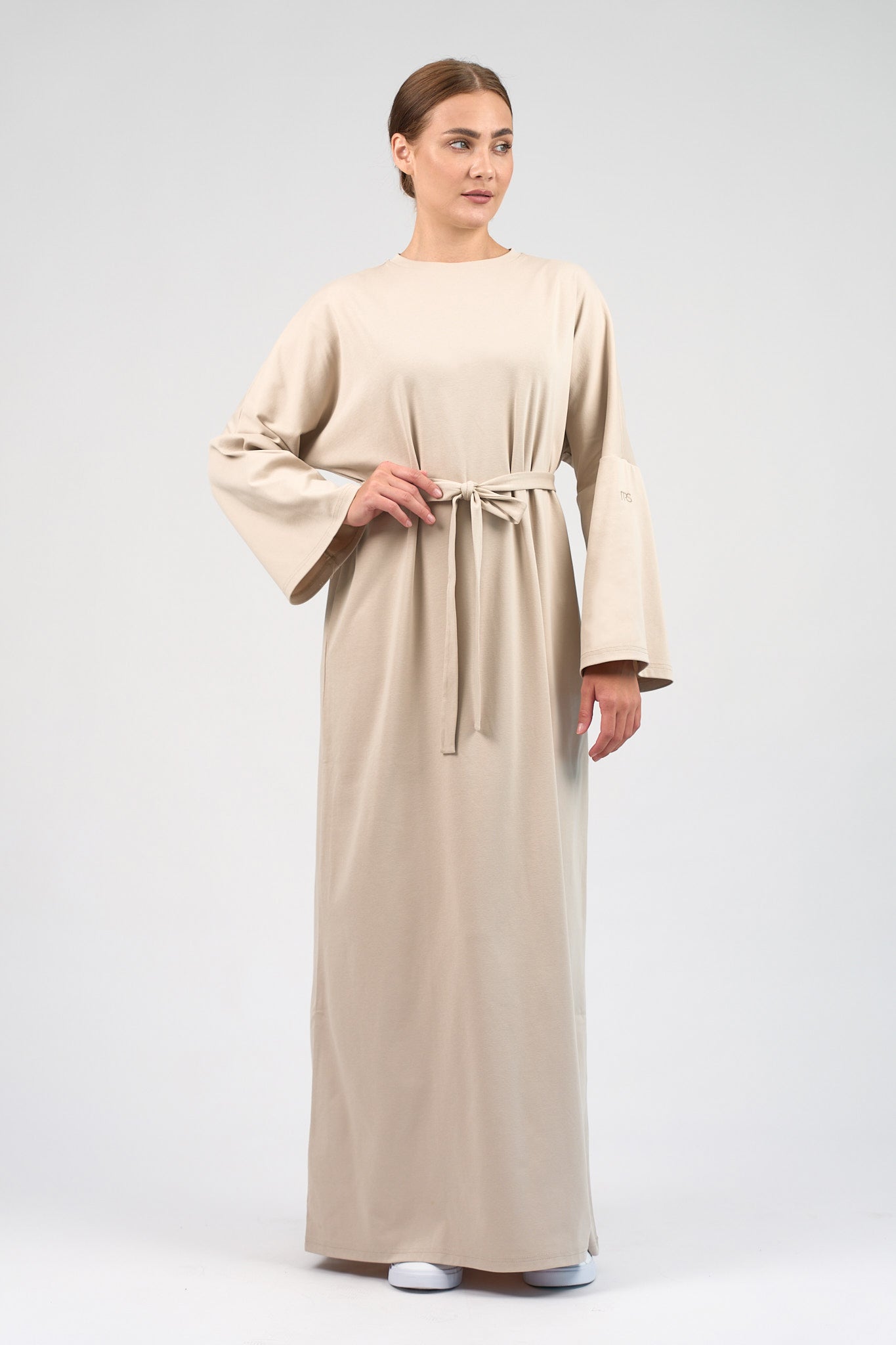 Colour: Mink. A woman holding the belt of the Cotton Maxi Dress she is wearing.