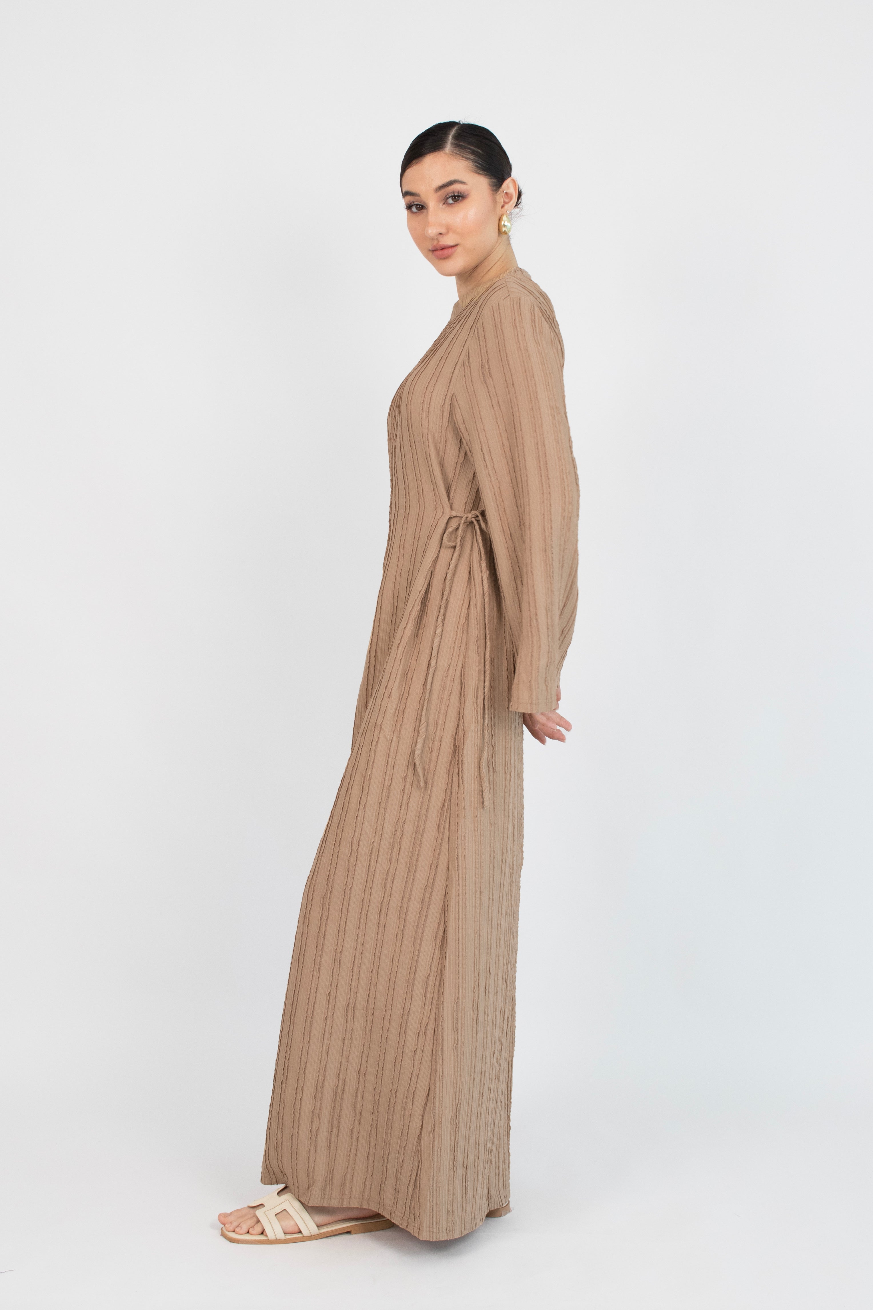 Colour description: Latte The girl is turned to the right in a textured bow detail dress.
