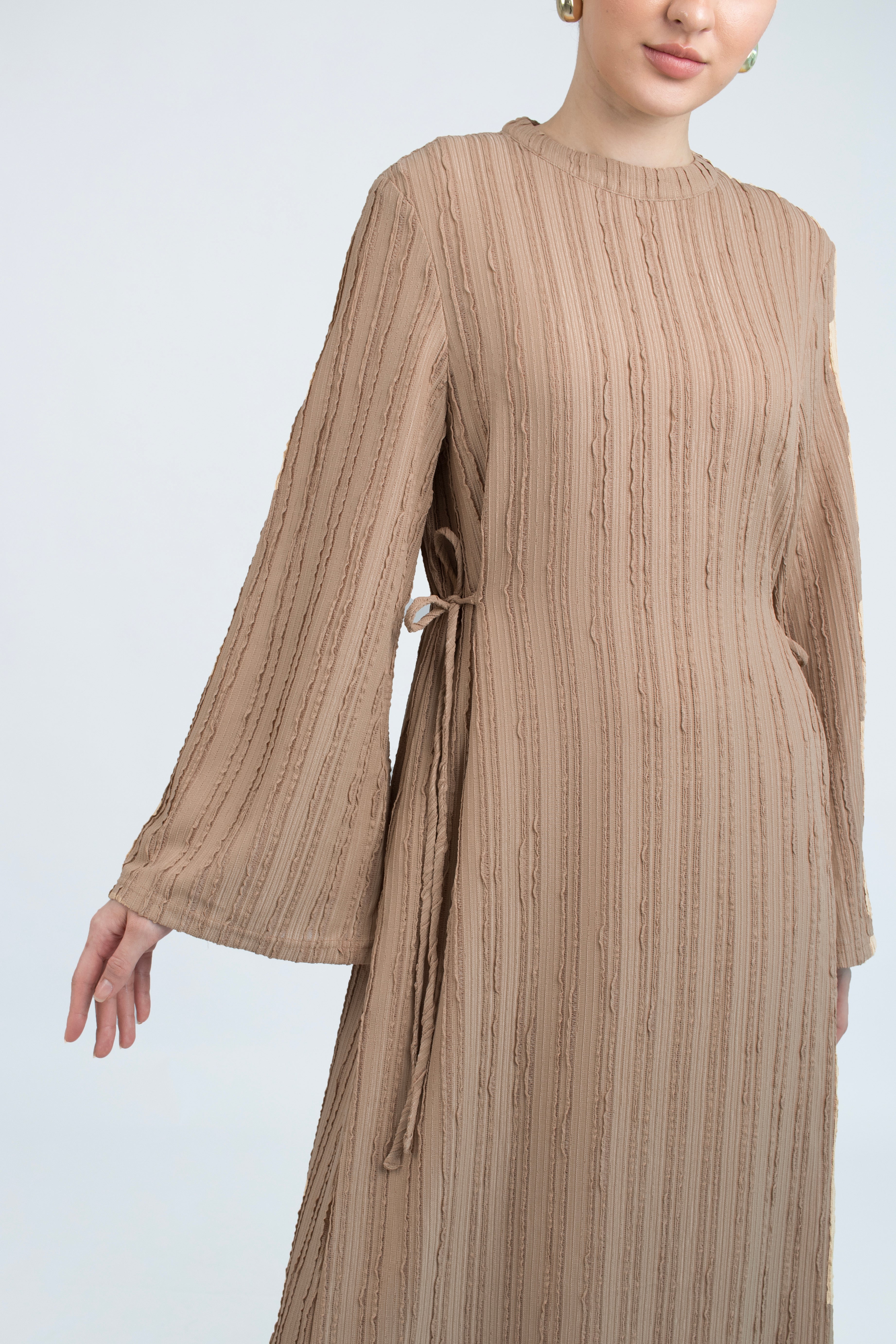 A close up of a girl posing in a bow dress. Colour description: Latte