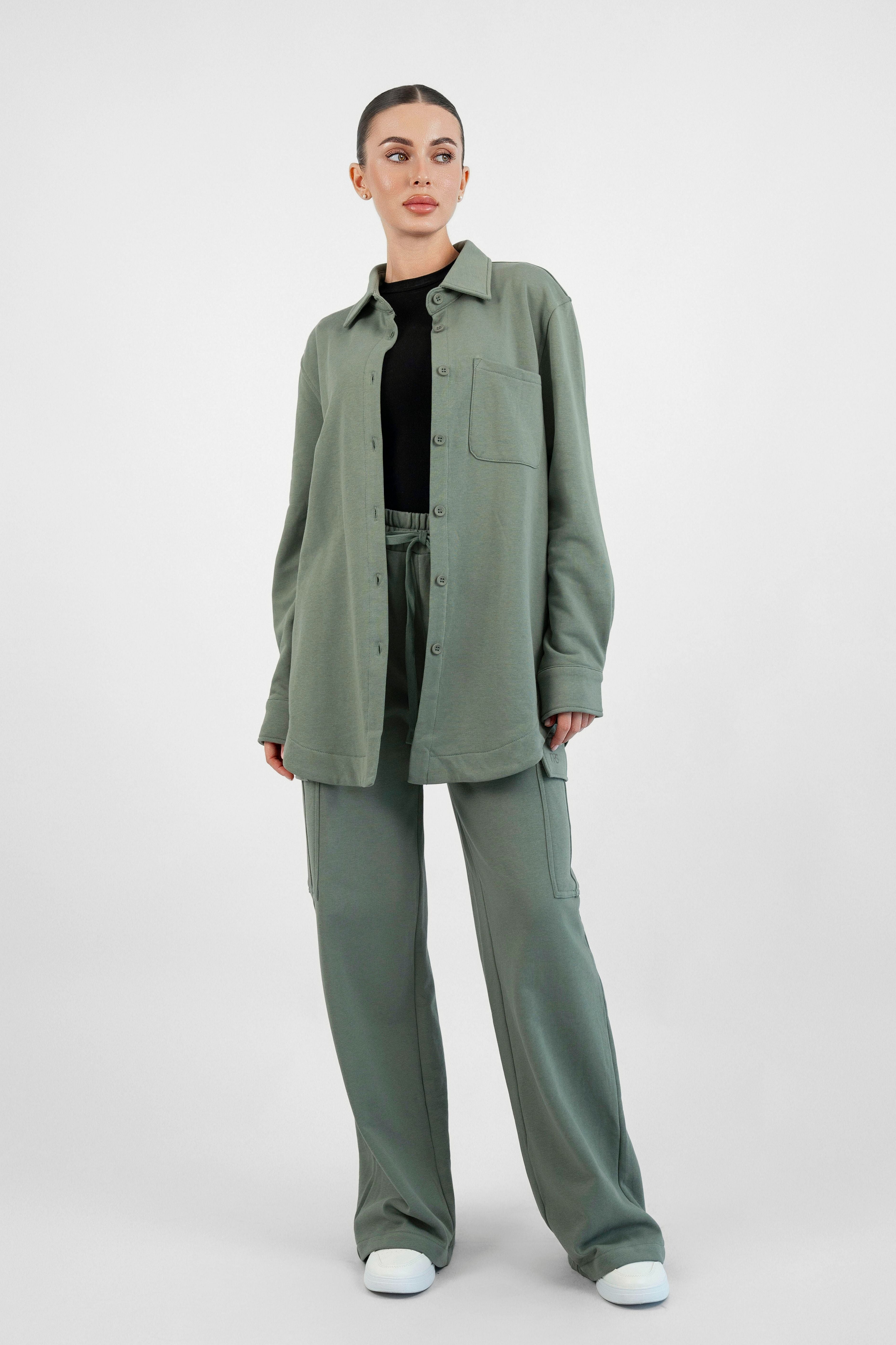 Colour: Oakmoss. A woman standing with her front towrads the camera in an Oversized Cotton Shacket.
