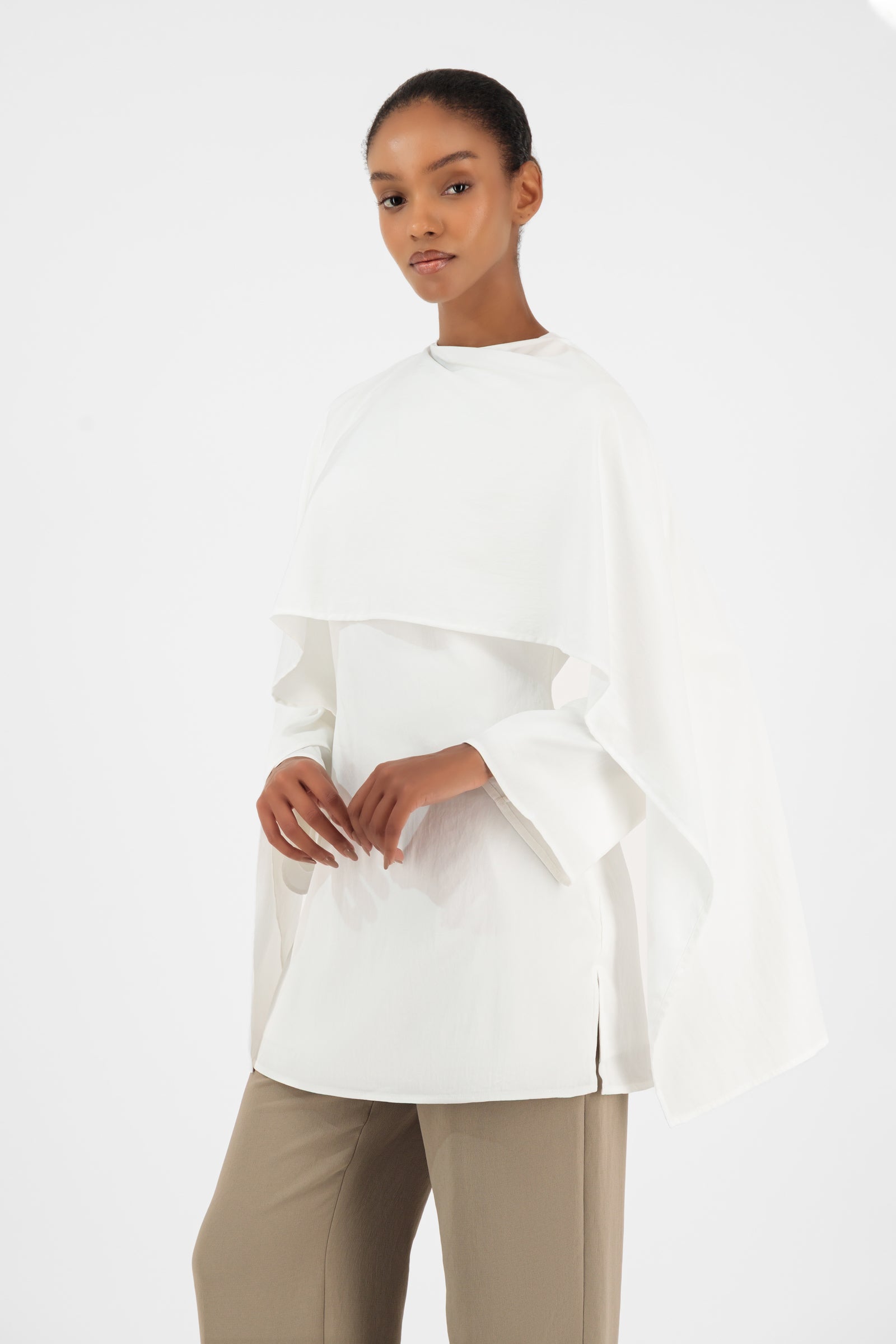 Girl posing in the white FARES tunic with wide sleeves and a refined layered neckline.
