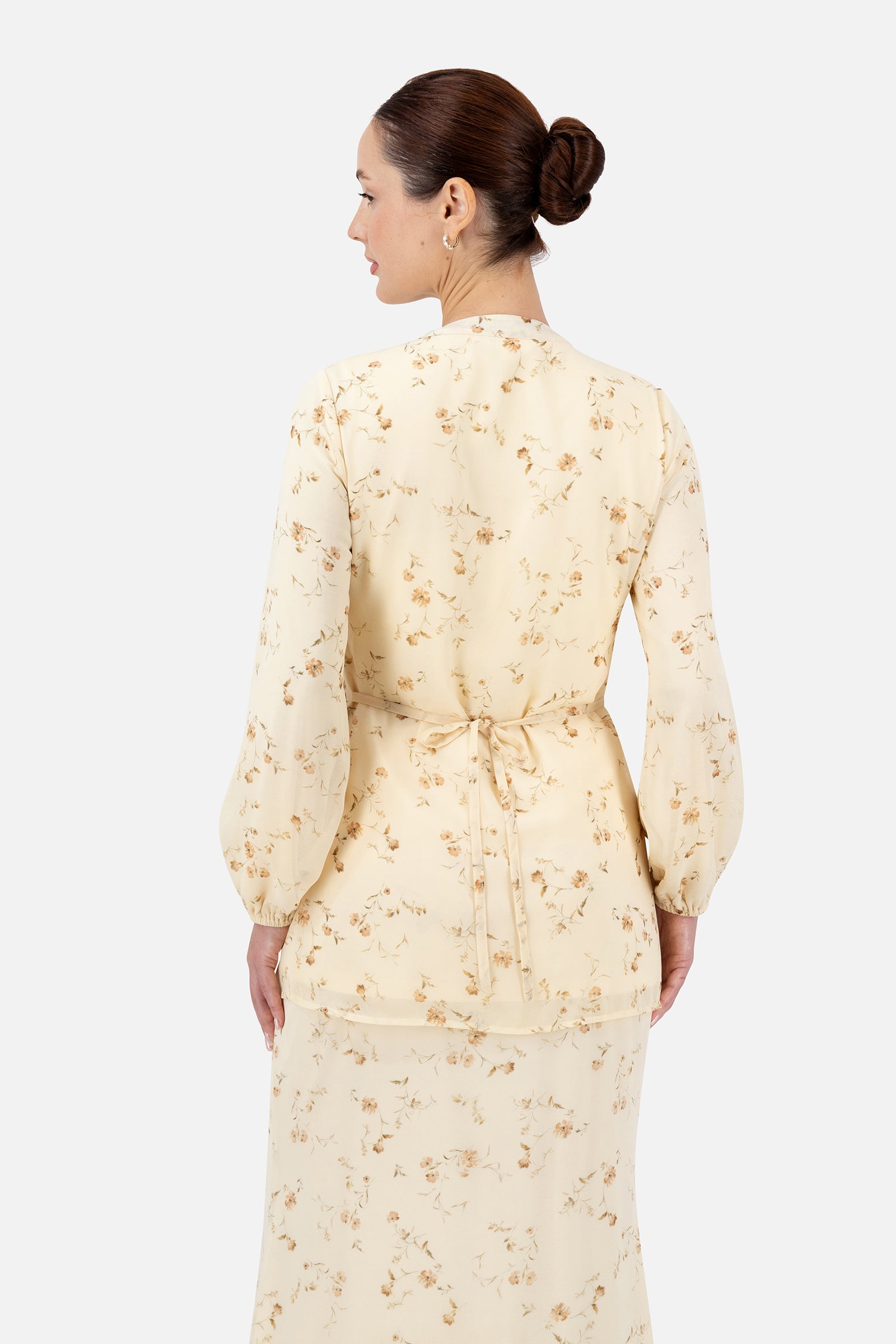 Back view of the Butterbloom blouse showcasing the elegant floral print and curved hem.
